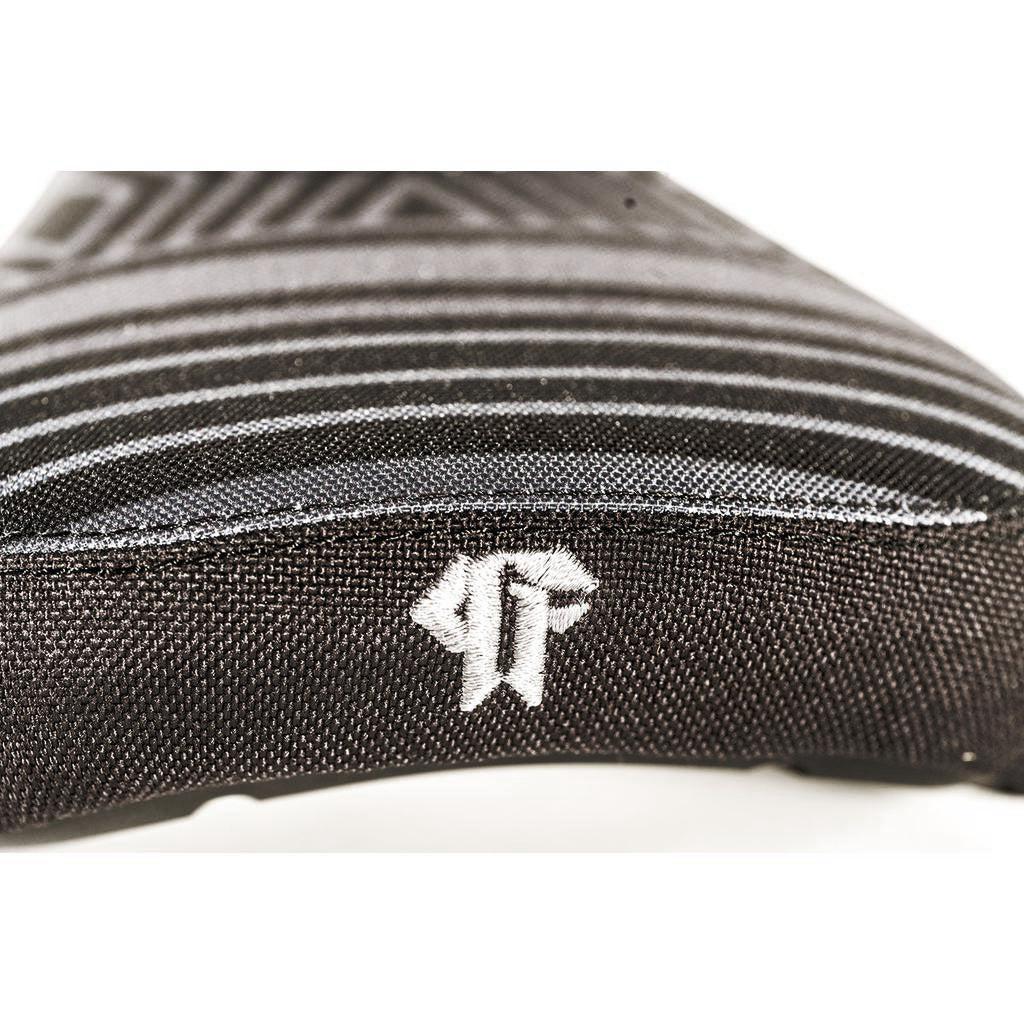 Detailed view of a black fabric featuring geometric patterns and a white embroidered logo resembling stylized letters, suggestive of the Colony Paterico Pivotal Seat's craftsmanship with its signature technology.