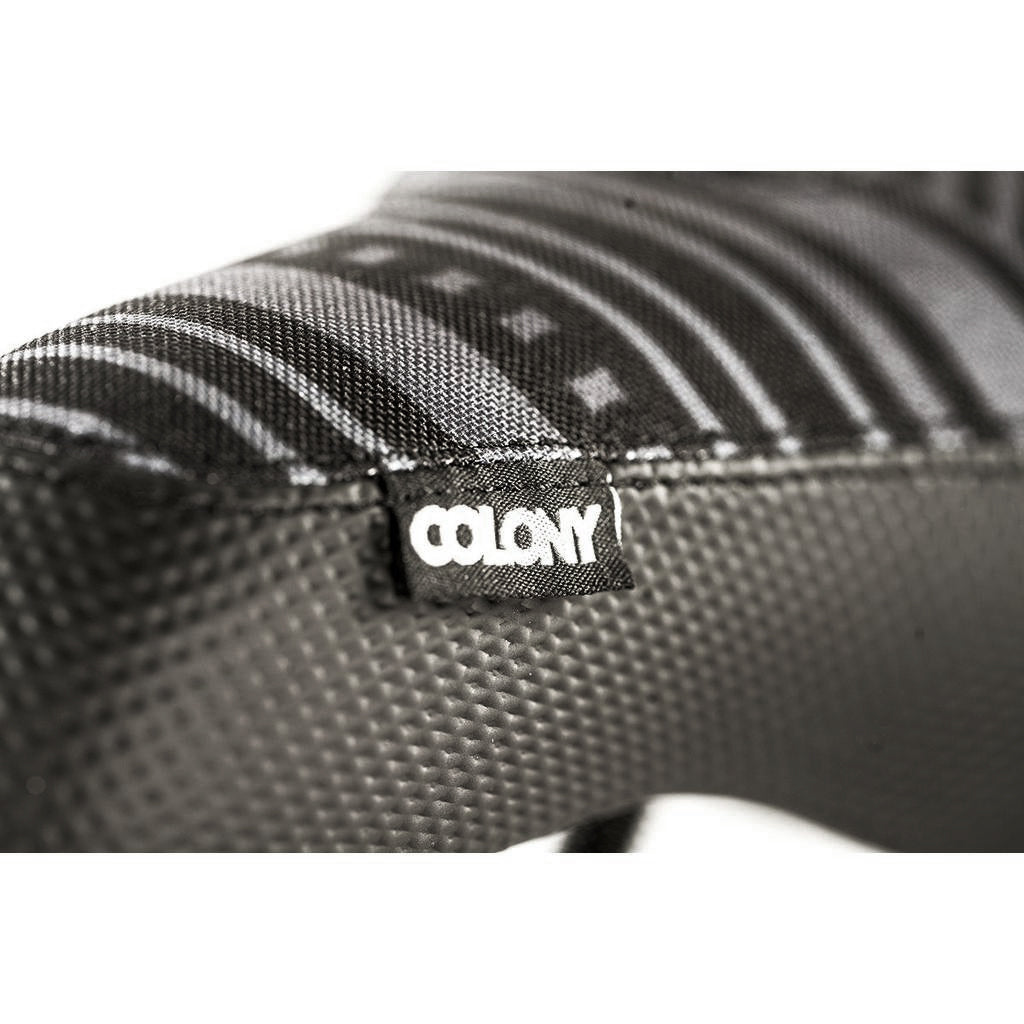 Close-up of a Colony Paterico Pivotal Seat label on textured black and gray fabric with geometric patterns.