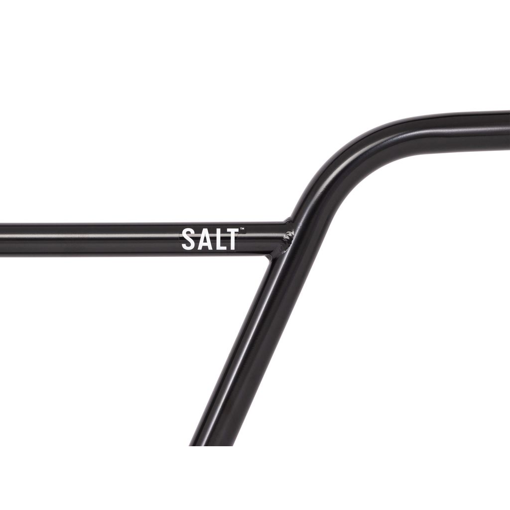 Close-up of a black metal bicycle frame featuring the word "SALT" in white lettering near a joint, complemented by sleek Salt Pro Bars for ultimate BMX performance.