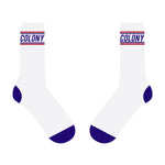 Depiction of the Colony BMX Logo Socks, showcasing a pair of white socks adorned with purple toes and heels. The bold "COLONY" text in purple contrasts beautifully against the backdrop, while vibrant red and purple stripes near the top enhance the style. These socks not only embody the spirit of Colony BMX but also highlight their status as proudly Australian Made.