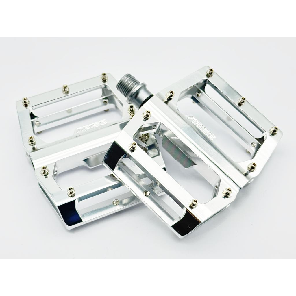 The Arise Xenon Expert Pedals are silver metal bicycle pedals with a flat platform design, expert CNC alloy body, and sealed bearing, showcased against a white background.