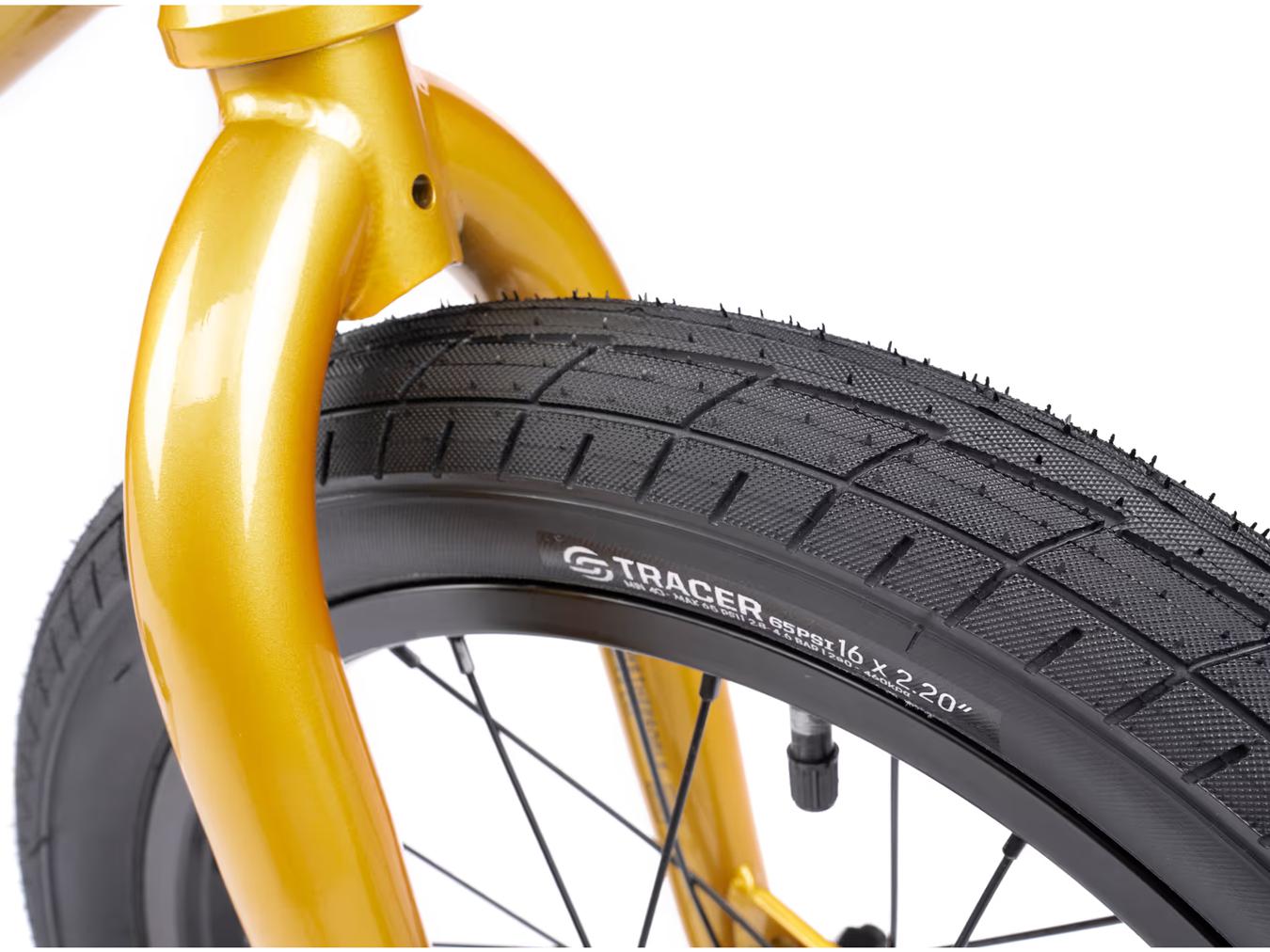 Close-up of a Wethepeople Seed 16 Inch Bike's front wheel, featuring a black treaded tire and sleek black spokes attached to a bright yellow fork.