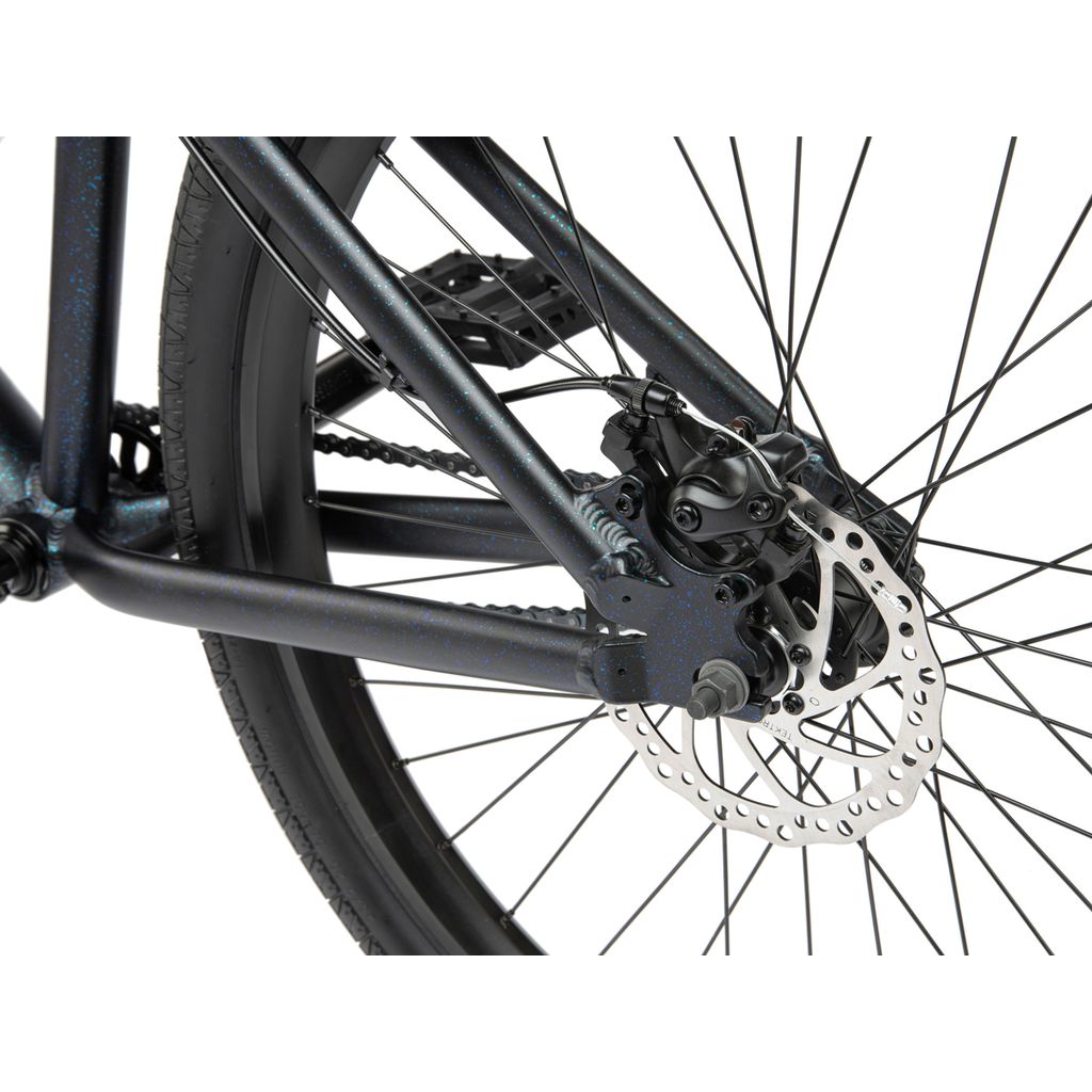 Close-up of the rear wheel of a Radio 26 Inch Legion Bike, highlighting the black spokes, Tektro disc brake rotor, and a section of the 6061-T6 alloy frame.