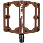 The Deity Black Kat Pedals boast a flat brown design with black pins, a centrally positioned logo, and a robust double sealed bearing system, making them an excellent choice for riders in search of dependable platform pedals.