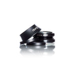 A stack of black, round lens filters rests elegantly on a reflective white surface, reminiscent of the precision found in the Demolition Headset 15mm Cap.