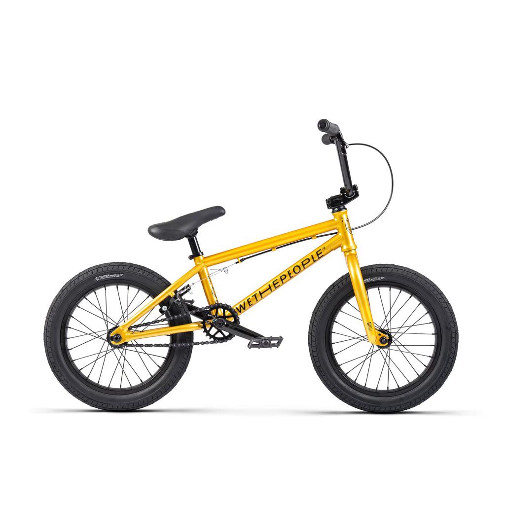 The Wethepeople Seed 16 Inch Bike showcases bold "WETHEPEOPLE" branding on its frame, featuring thick black tires and Salt Rookie Tubular Chromoly Cranks. Displayed from the side against a pristine white background, this vibrant yellow BMX shredder is a visual standout.