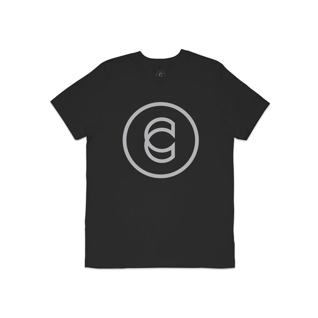 The Cinema Icon T-Shirt is a black top featuring a large silver circular logo with a stylized "C" at its center, offering a modern look ideal for any movie outing.