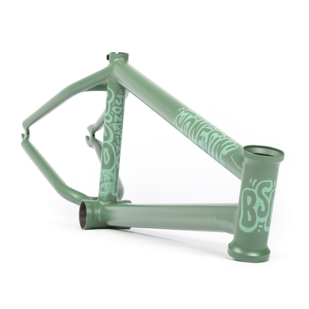 The BSD Jonesin Frame (2021) showcases a green bicycle frame adorned with light blue graffiti-style designs, featuring a BMX logo on the head tube and street-inspired geometry, set against a white background.