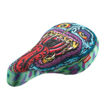 A Pivotal Fat bicycle seat called the Odyssey IG Hot Seat, showcasing vibrant artwork of a monstrous face with an extended tongue and "Odyssey" above sharp teeth on a multicolored, abstract pattern background. Participate in the Odyssey Instagram hot seat competition for a chance to win this striking design!