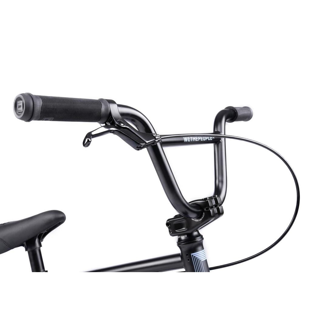 Close-up of black handlebars with grips and a brake lever on the left side, highlighting the sleek design of the Wethepeople Riot 14 Inch BMX Bike, set against a plain white background.