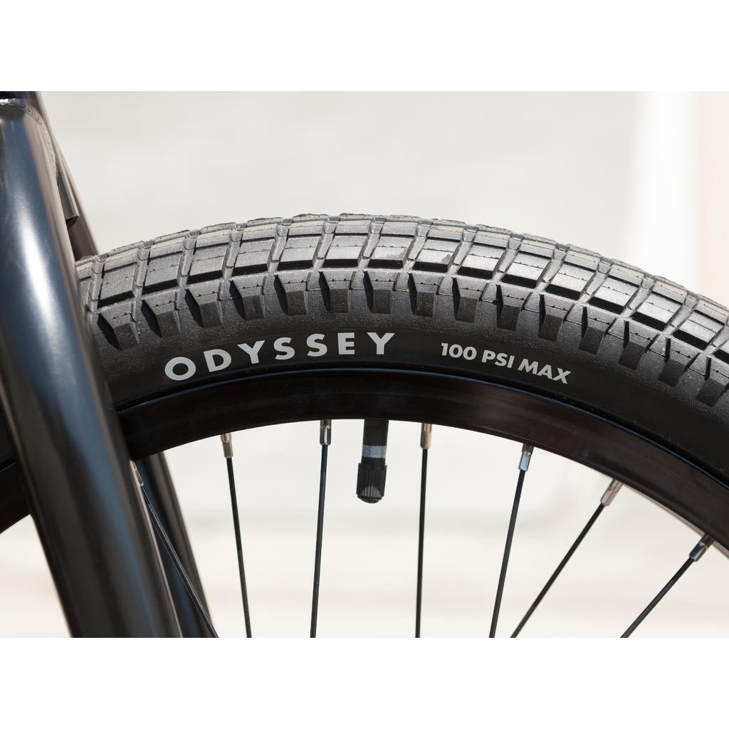 Close-up of the Sunday Wave Length 20 Inch (Gary Young) bike tire reads "ODYSSEY 100 PSI MAX," mounted on a black rim with visible spokes.