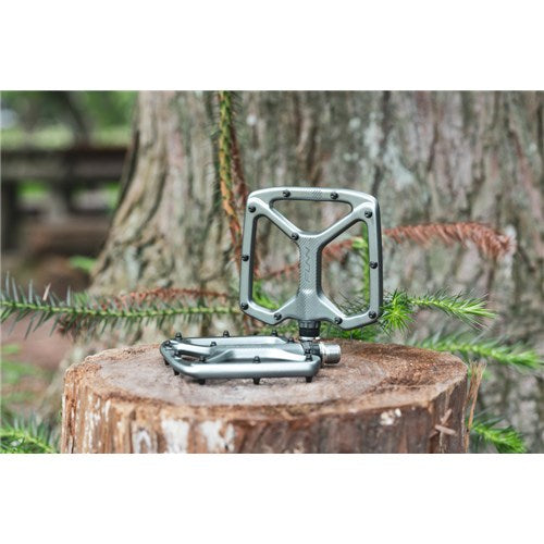 The Funn Python V2 Alloy Pedal rests on a tree stump, adding stability against a backdrop of green foliage and bark.