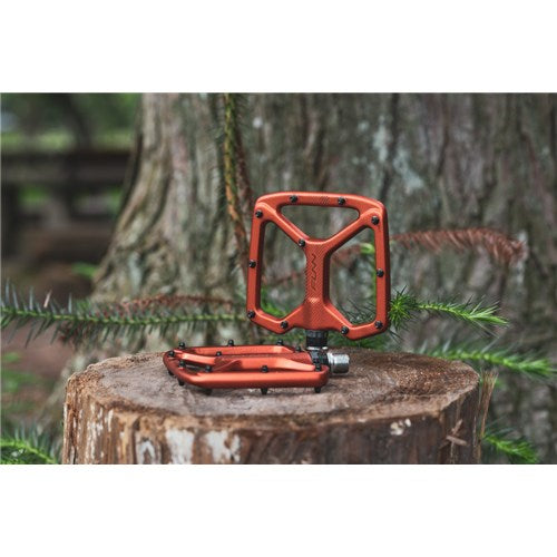 Funn Python V2 Alloy Pedals, renowned for performance and stability, are elegantly placed on a tree stump with a blurred forest backdrop.