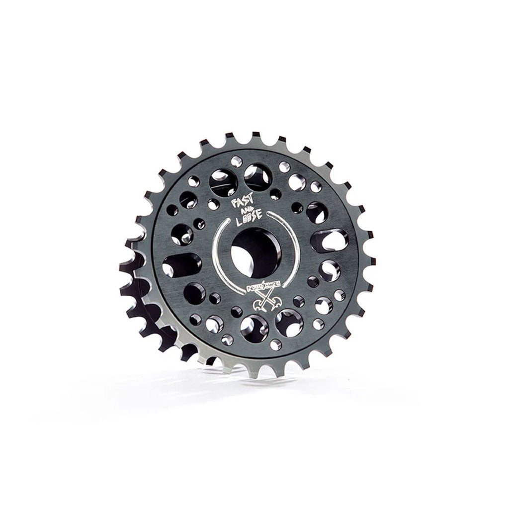 A dark-colored, multi-hole Demolition Fast and Loose Limited Edition sprocket wheel with engravings, designed for mechanical or automotive use, displayed against a white background.