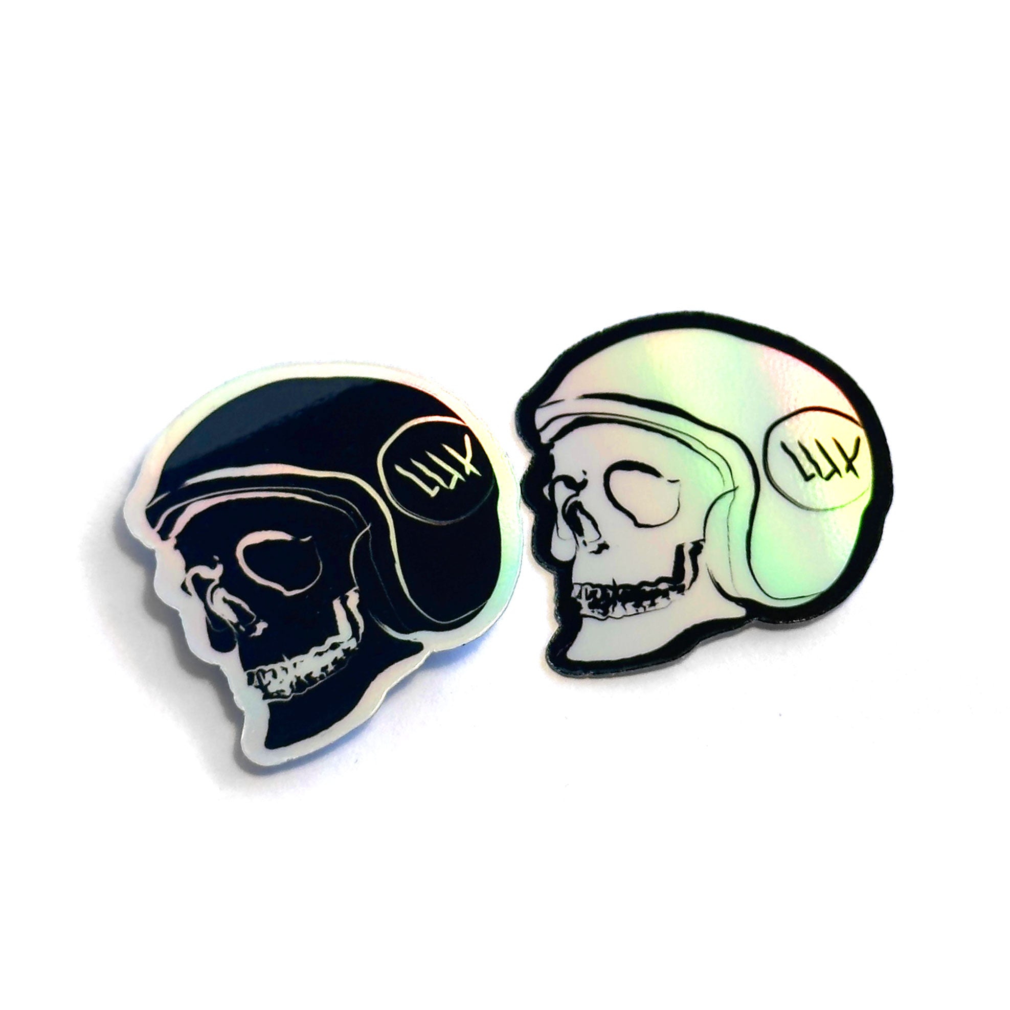 The LUXBMX Skull Holo Stickers feature two striking skull illustrations, each adorned with a helmet—one in black and the other in a captivating holographic design—with "LUX" prominently displayed on the sides. Made from durable waterproof vinyl, these stickers are ideal for BMX enthusiasts and dedicated LUXBMX fans.