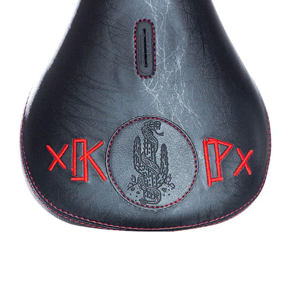 The Demolition Kevin Peraza Seat is a black leather bicycle seat with red stitching, featuring an embroidered dragon and bold red geometric symbols.