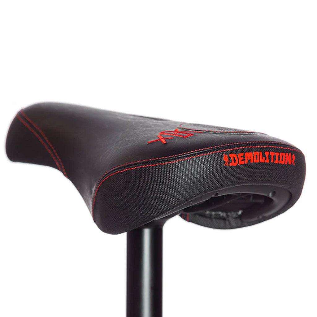 The Demolition Kevin Peraza Seat is black with red stitching and a "Demolition" logo on the side, featuring a textured canvas top, microfiber sides, and comes mounted on a seat post for an exceptional ride.