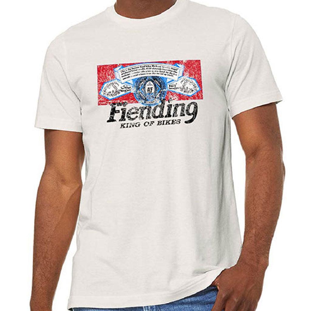 A person wearing a Fiend Shirt King Of Bikes (Vintage White) with a colorful graphic and the text "Fiending King of Bikes" on the front.