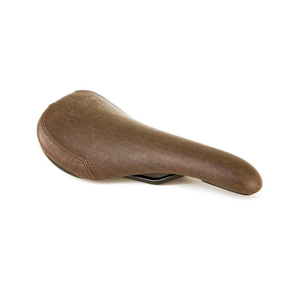 The Fly Bikes Motosierra Railed Seat, a brown bicycle seat made of smooth synthetic leather, is shown from the side against a plain white background. It includes a railed base for enhanced support and stability.