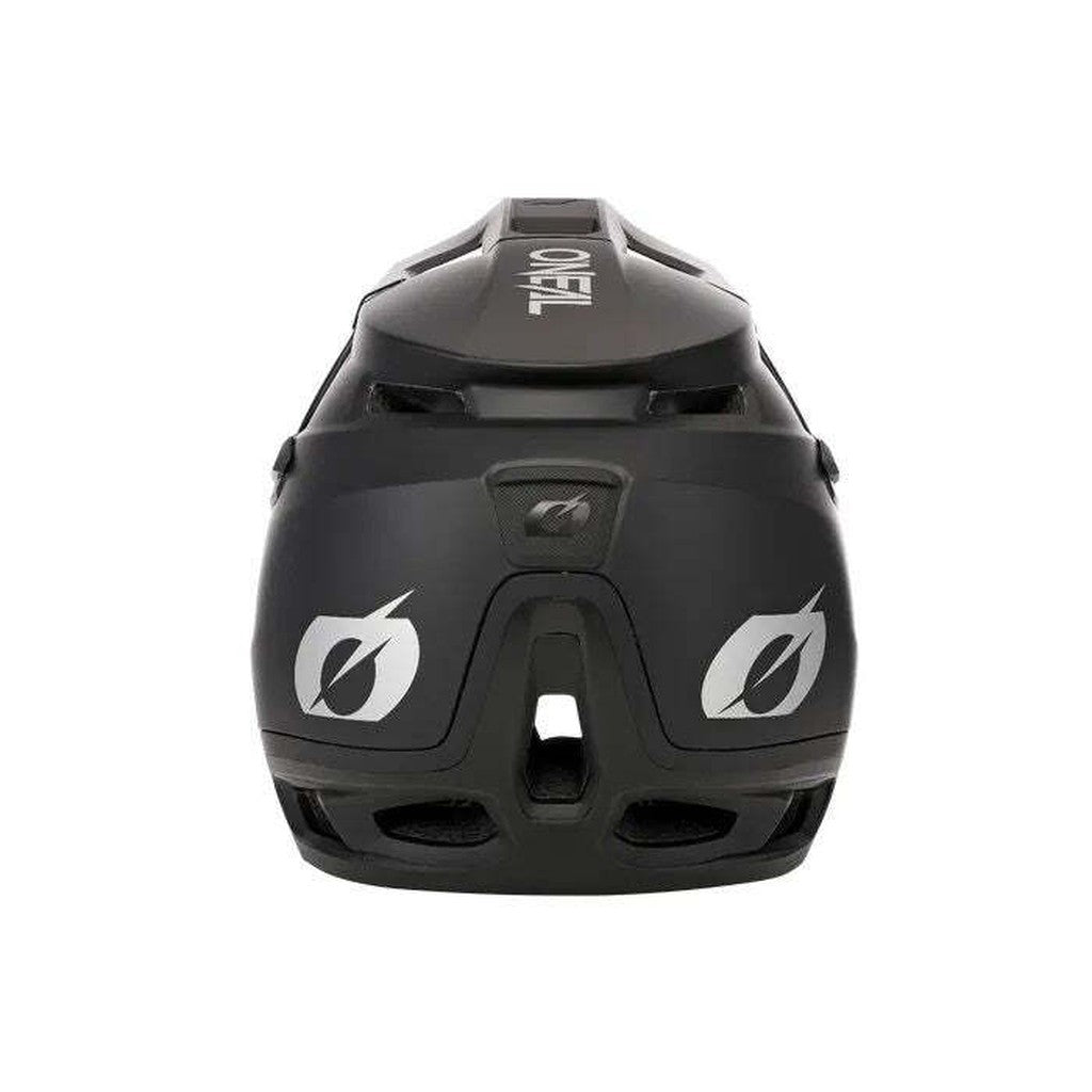 The Oneal Transition Helmet in black, viewed from the rear, features vent openings for maximum airflow cooling and proudly displays the brand logo. It is designed with lightweight materials and incorporates rotational impact absorption technology.