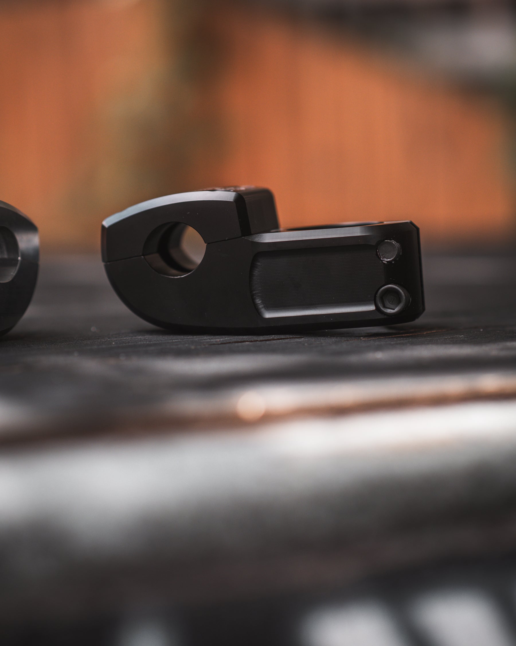 Close-up of a Demolition Josh Dove Stem resting on a surface, with a blurred background highlighting its black metal design.