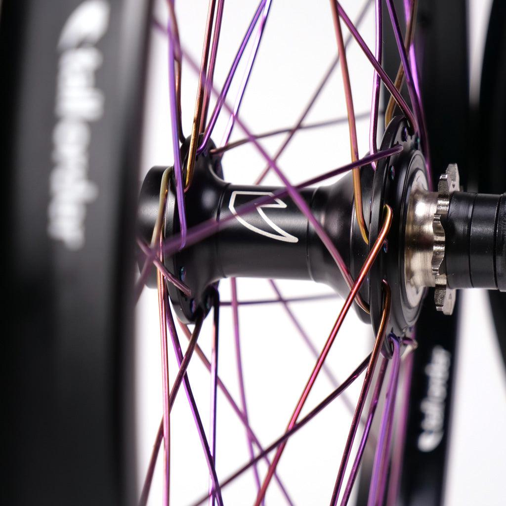 Close-up image of a Tall Order Drone x Air Custom Wheelset featuring multi-colored spokes, against a white background.