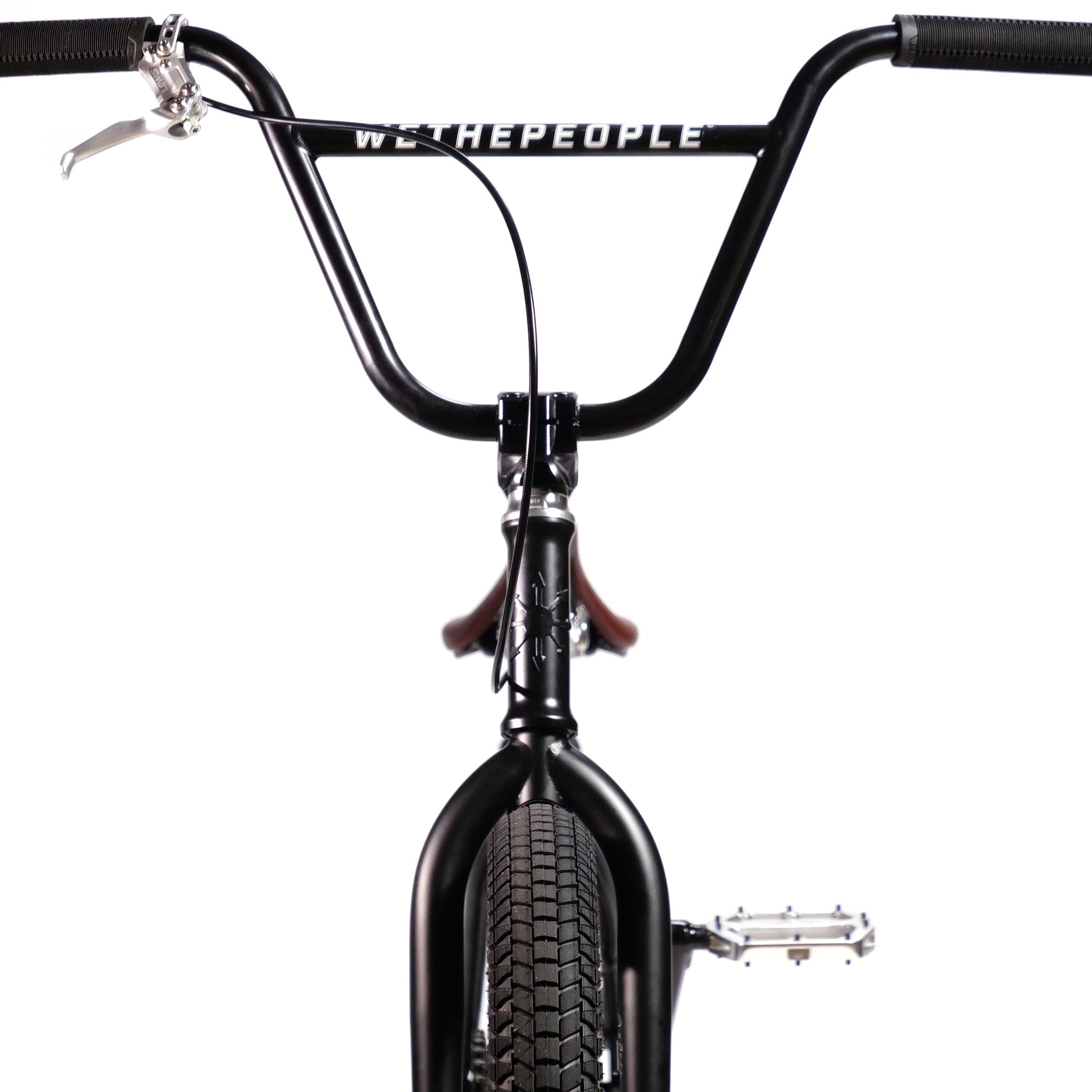 Front view of a black BMX bike with "Wethepeople Chaos Machine" written on the handlebars, showing the handlebars, tire, and one pedal on the Wethepeople Chaos Machine 22 Inch Custom Bike.