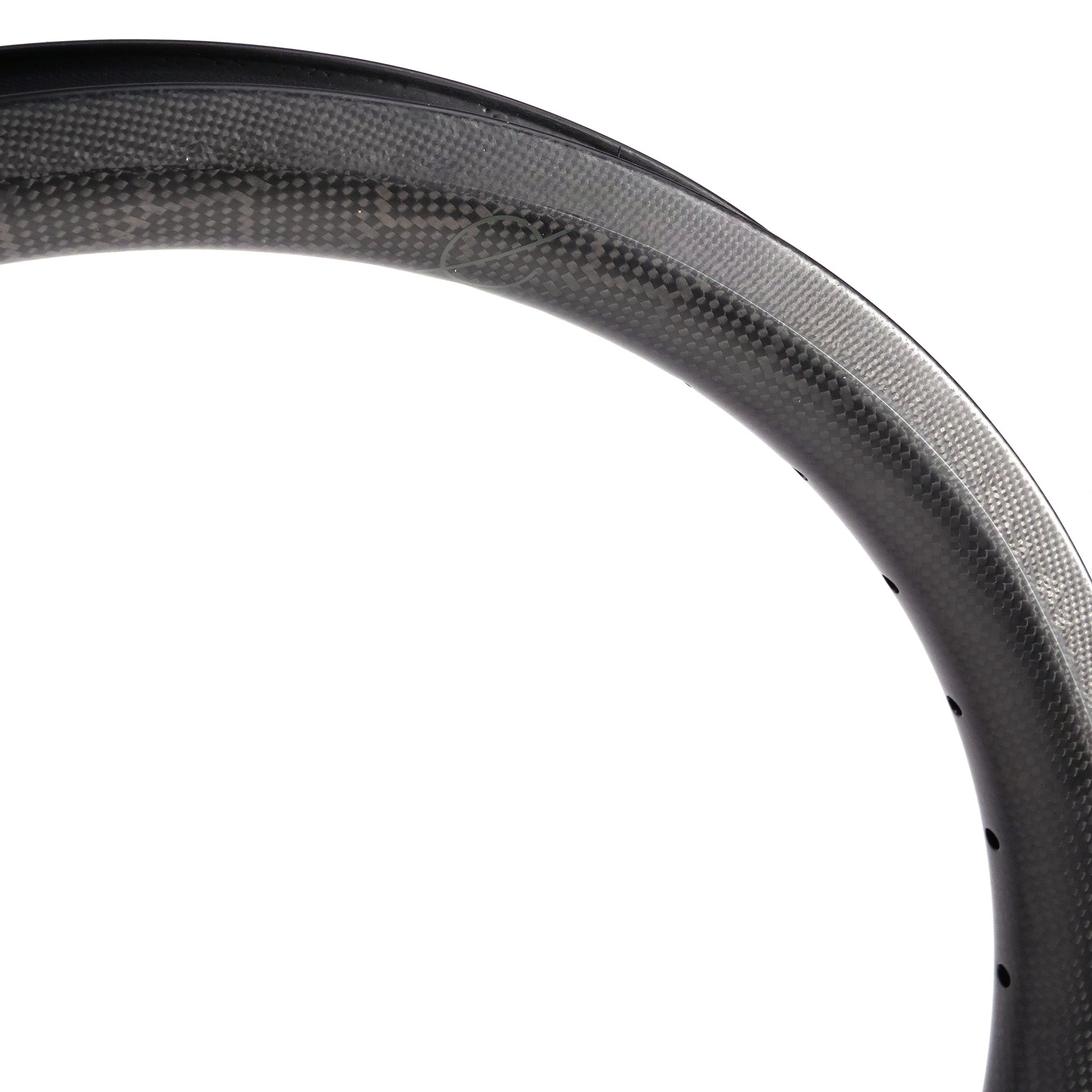 Close-up of a section of a Spectre V2 Carbon Fibre 20 Inch Brake Rim with visible texture and curvature, featuring 4D drilled holes.