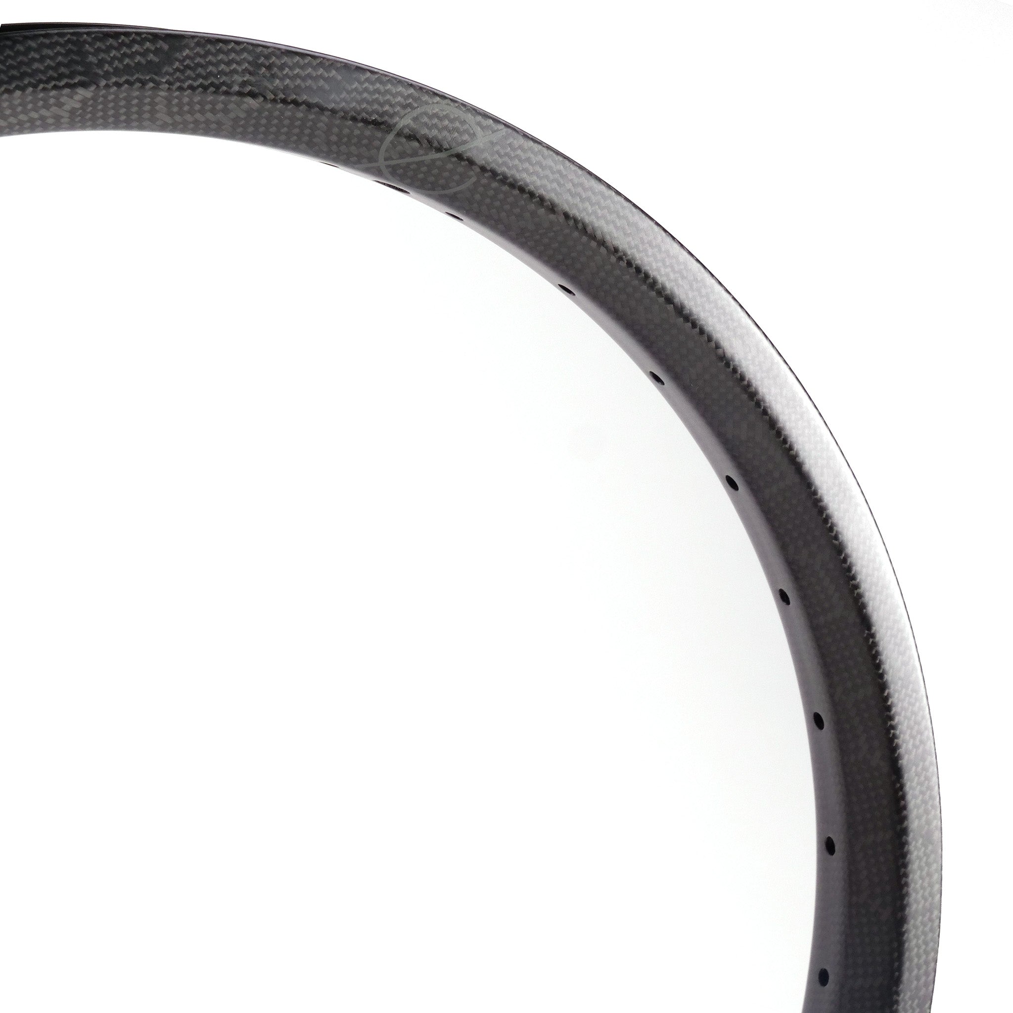 A close-up view of a Spectre NME Carbon Fibre 20 Inch Brakeless Rim with a matte finish, showing the perforations for spokes against a plain white background—a perfect choice for freestyle riders.