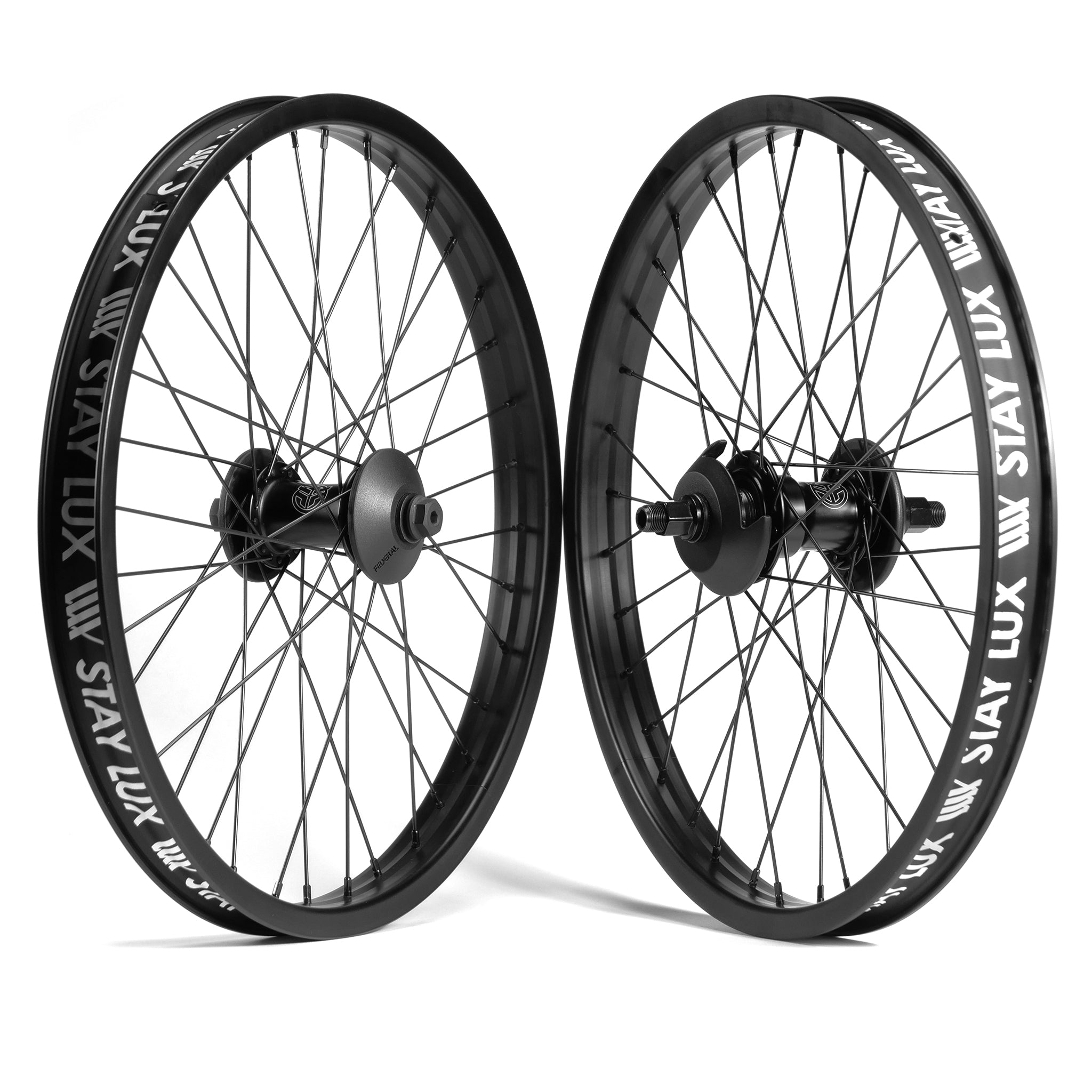 Two black bicycle wheels standing upright, featuring black spokes and printed with the text "STAY LUX" on the rims. These Federal Motion x Odyssey Stage 2 Custom Wheelsets are positioned against a white background.