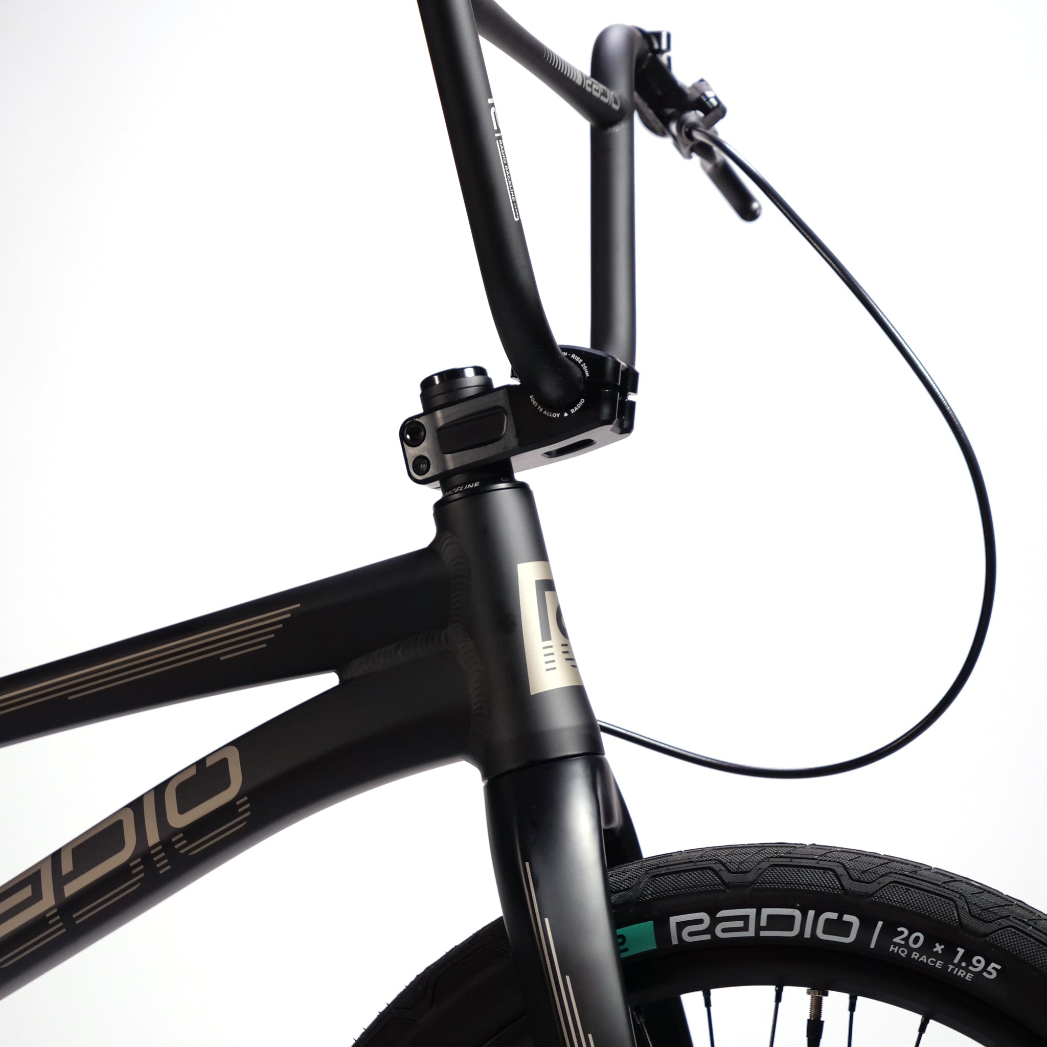 Close-up view of the handlebars, front fork, and wheel of a black "Radio Quartz Pro XL Bike 2025," showcasing its lightweight hydro-formed frame, brake cable, and tires with visible tread pattern.