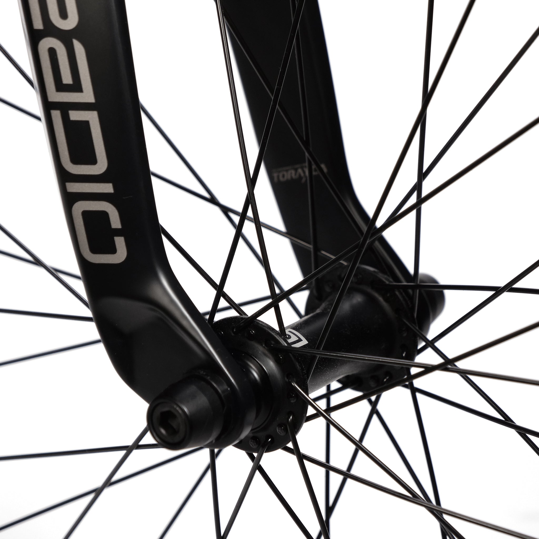 Close-up of a bicycle wheel with black spokes and a black fork. The fork of the Radio Quartz Pro XXL Bike 2025 has the word "TORAY" printed vertically on it, complementing the lightweight hydro-formed frame.