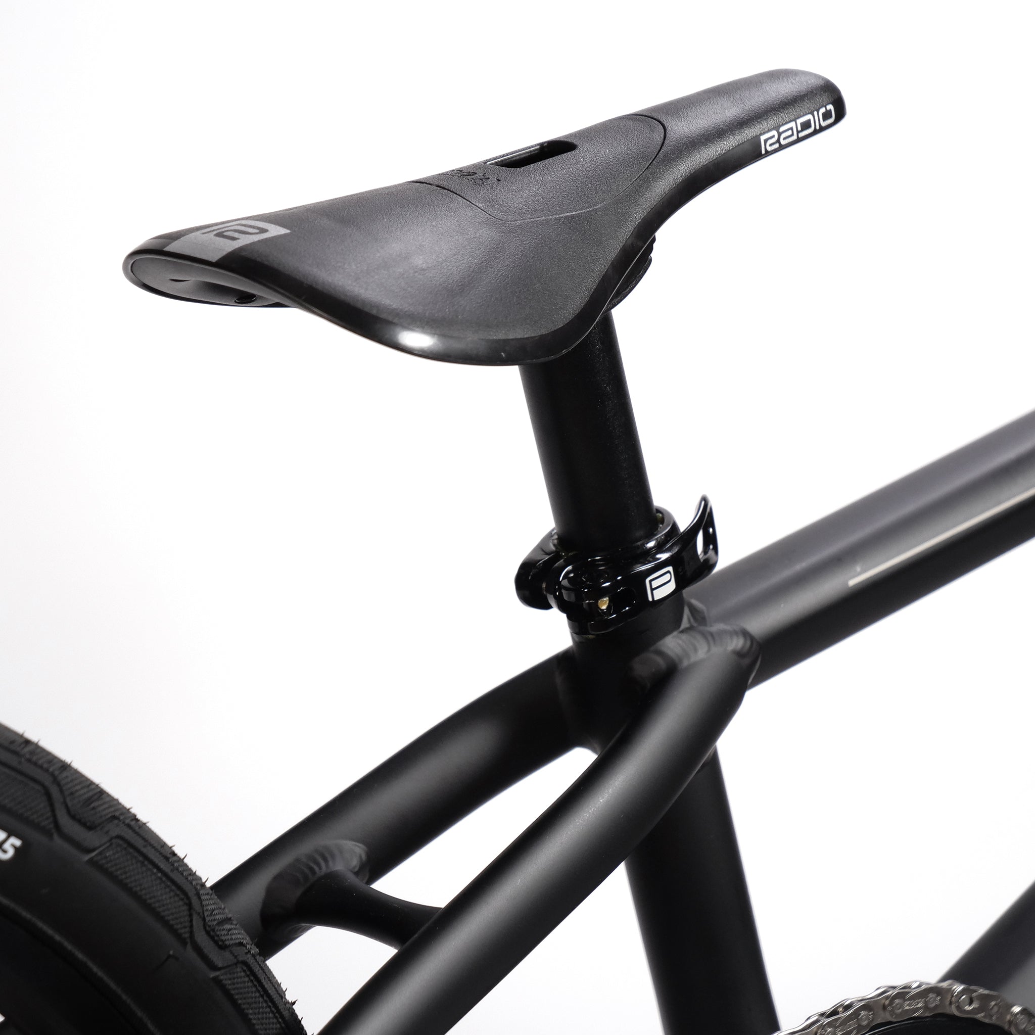 Close-up image of a black bicycle seat and seat post on a Radio Quartz Pro XXL Bike 2025 with a black-framed, lightweight hydro-formed frame against a white background.