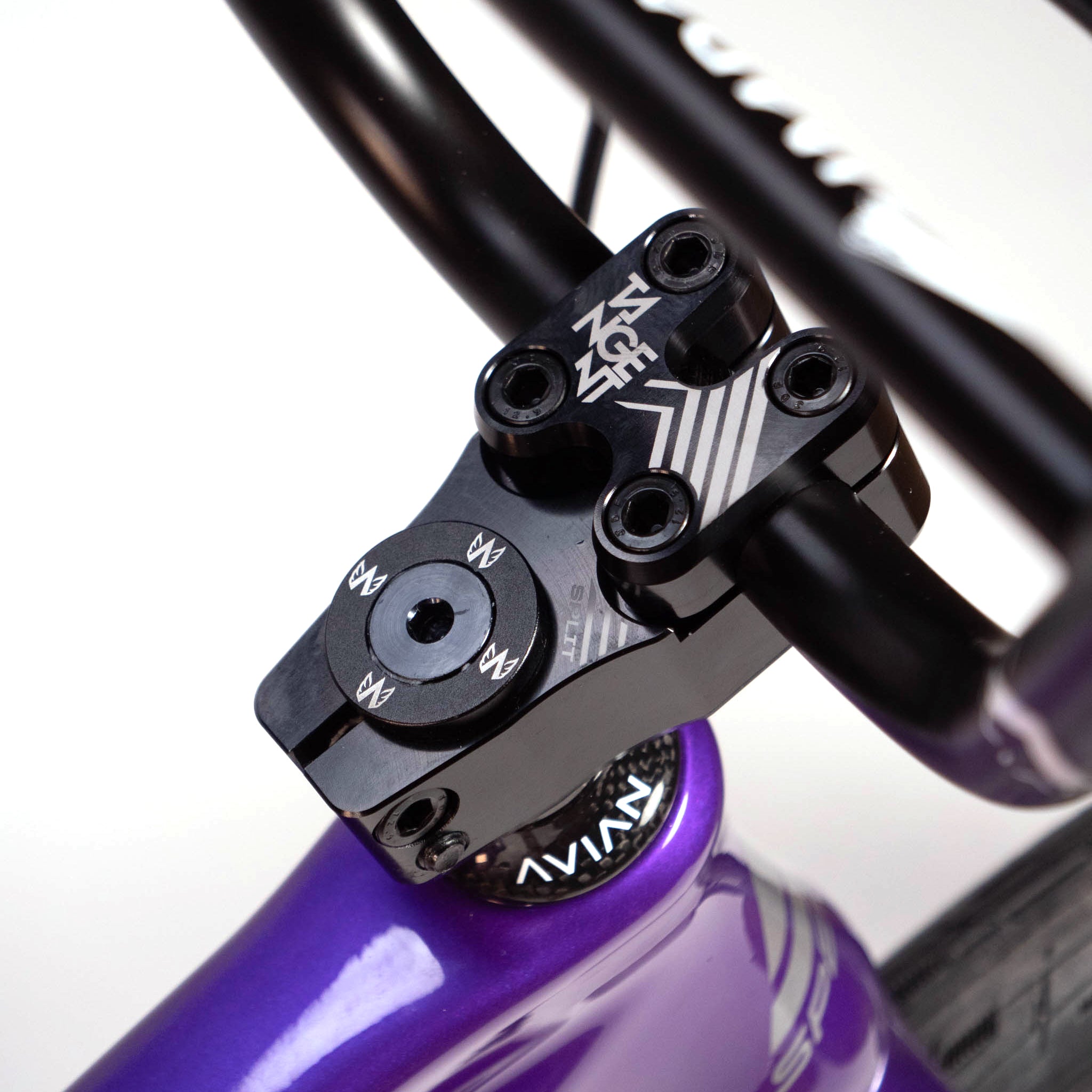 Close-up image of a black bicycle handlebar stem marked "Avian Gear" attached to a purple Speedco Velox Evo Pro XXXL Custom Bike frame. The handlebar stem, secured with multiple bolts, showcases the precision engineering of this custom race bike.