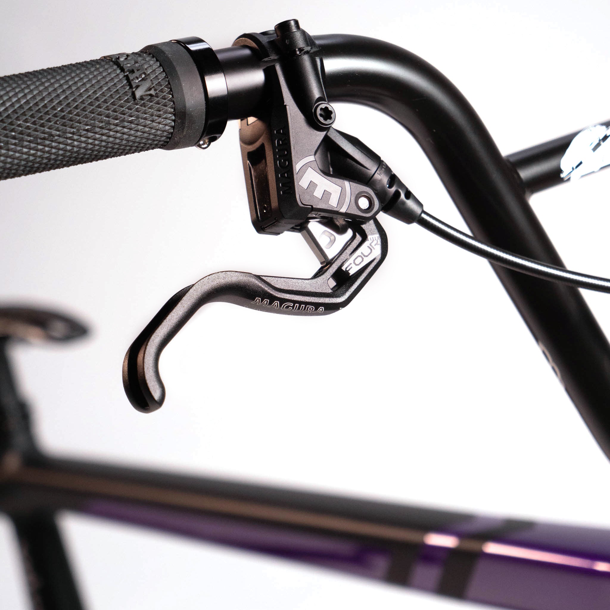 Close-up of a black bicycle brake lever attached to the handlebar of a Speedco Velox Evo Pro XXXL Custom Bike, featuring a textured grip for the ultimate control on this pro custom race bike.