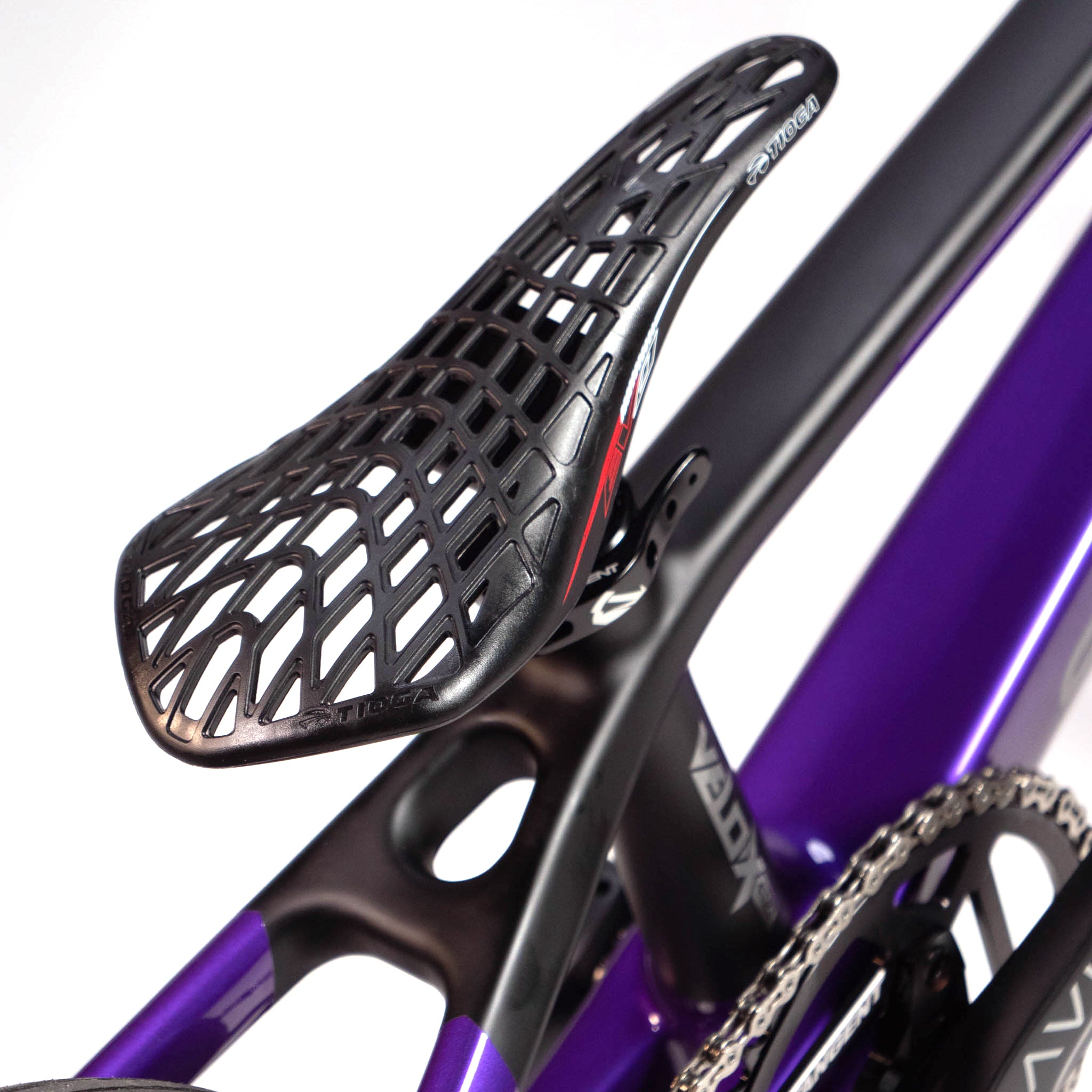 Close-up of a black, lattice-structured bike saddle mounted on a purple Speedco Velox Evo Pro XXXL Custom Bike frame.