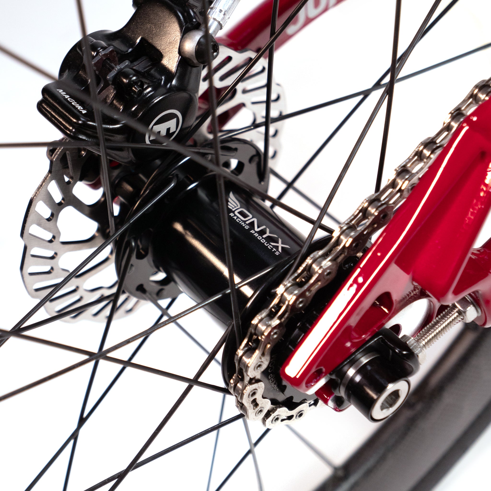 Close-up of a custom Meybo Holeshot Junior bike's rear wheel hub and disc brake assembly, featuring an Onyx Pro HG disc hub labeled "Onyx" and red frame components. The chain is visible, connecting the drivetrain of this custom race bike.