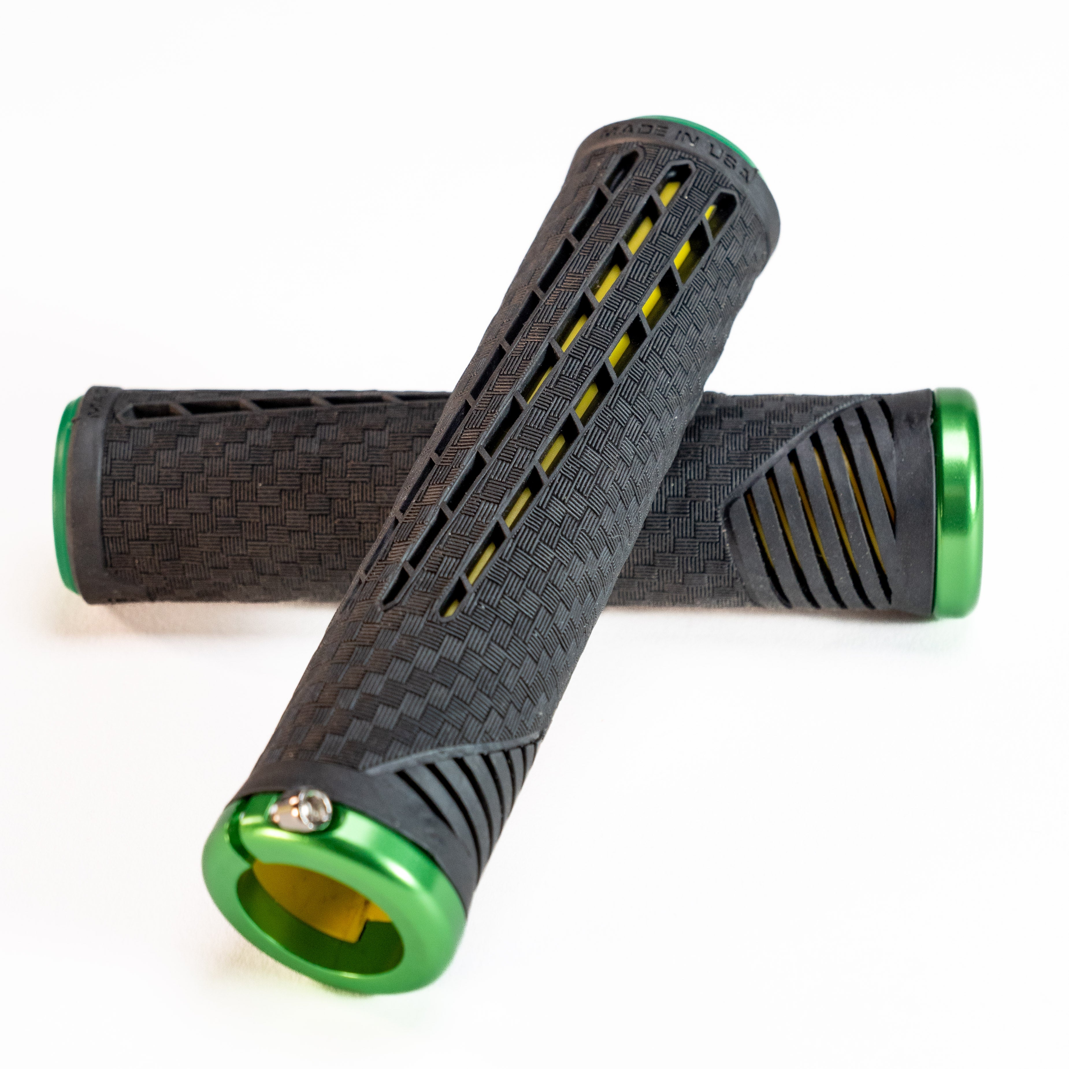 Two black ODI CF Lock On Grips V2.1 Izaac Kennedy Signature bicycle handlebar grips with green end caps and textured surfaces, arranged in a crisscross pattern on a white background, closely resemble the original design.