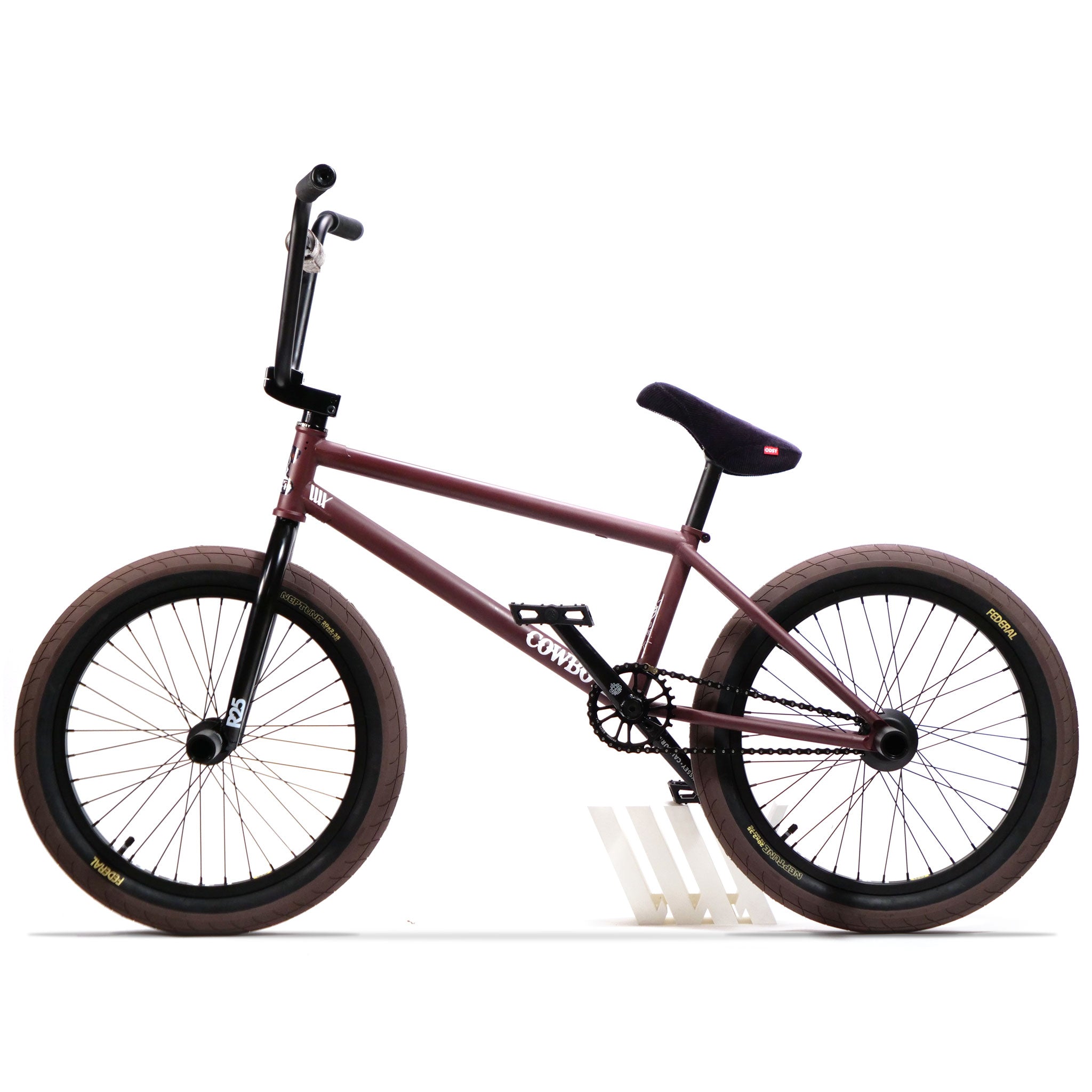 Side view of the Federal CowBoyd Custom 20 Inch Bike featuring a maroon frame, brown tires, and black Odyssey handlebars on a white background.