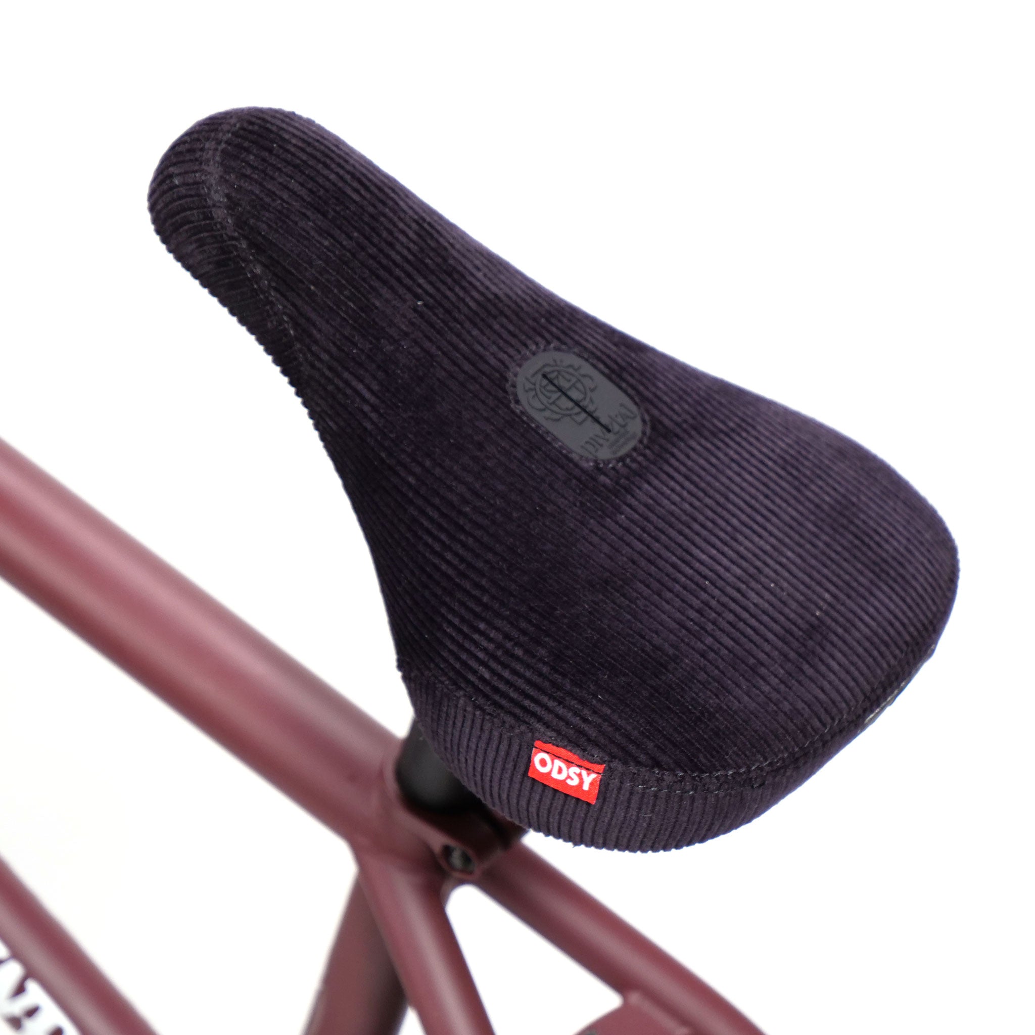 Close-up of the Federal CowBoyd Custom 20 Inch Bike seat, featuring a dark corduroy fabric and a red "ODSY" tag, mounted on a sleek brown frame.