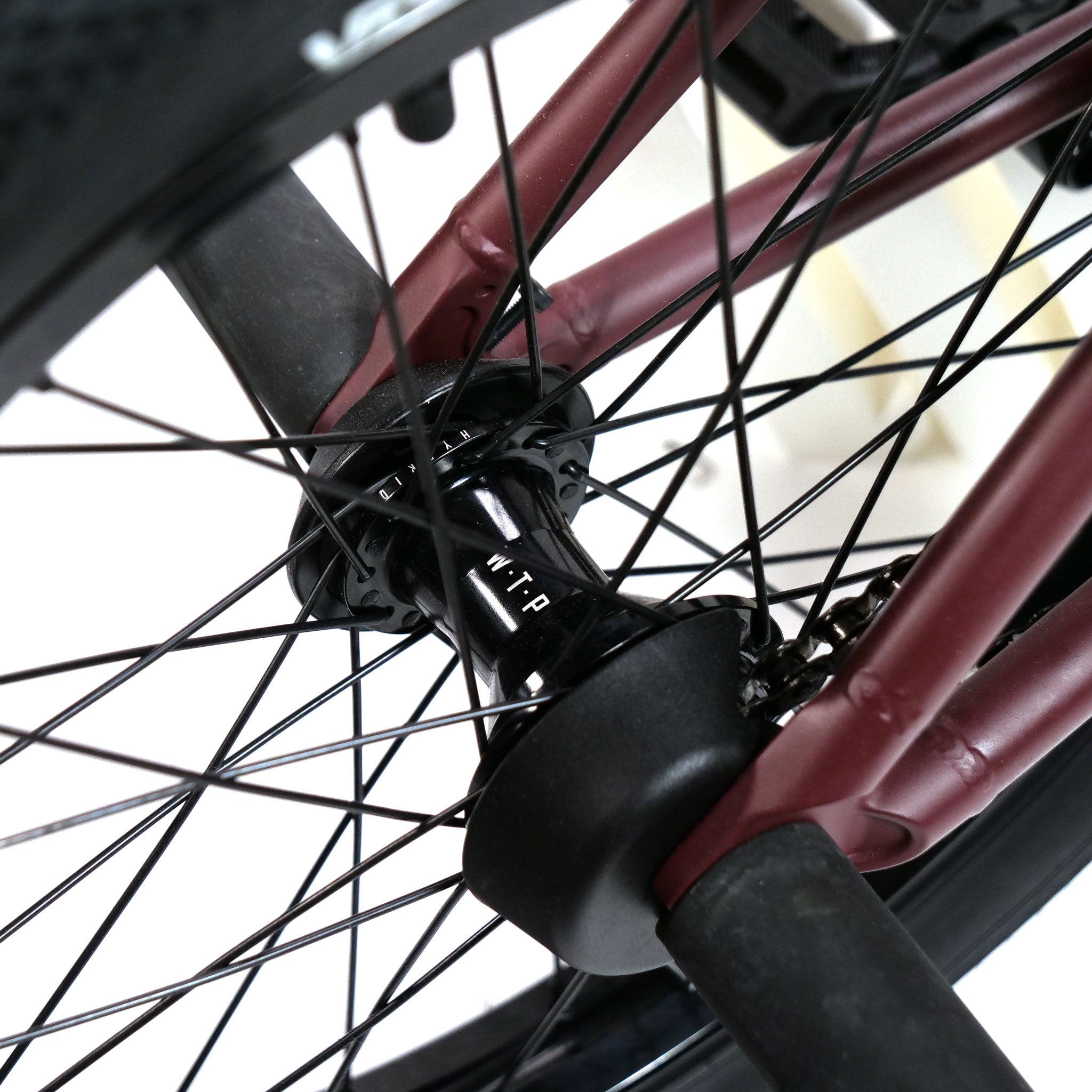 Close-up of the wheel hub with black spokes and a maroon frame of the Federal YUNGBOYD Custom 18 Inch Bike, featuring sleek aftermarket parts for a freestyle custom setup.