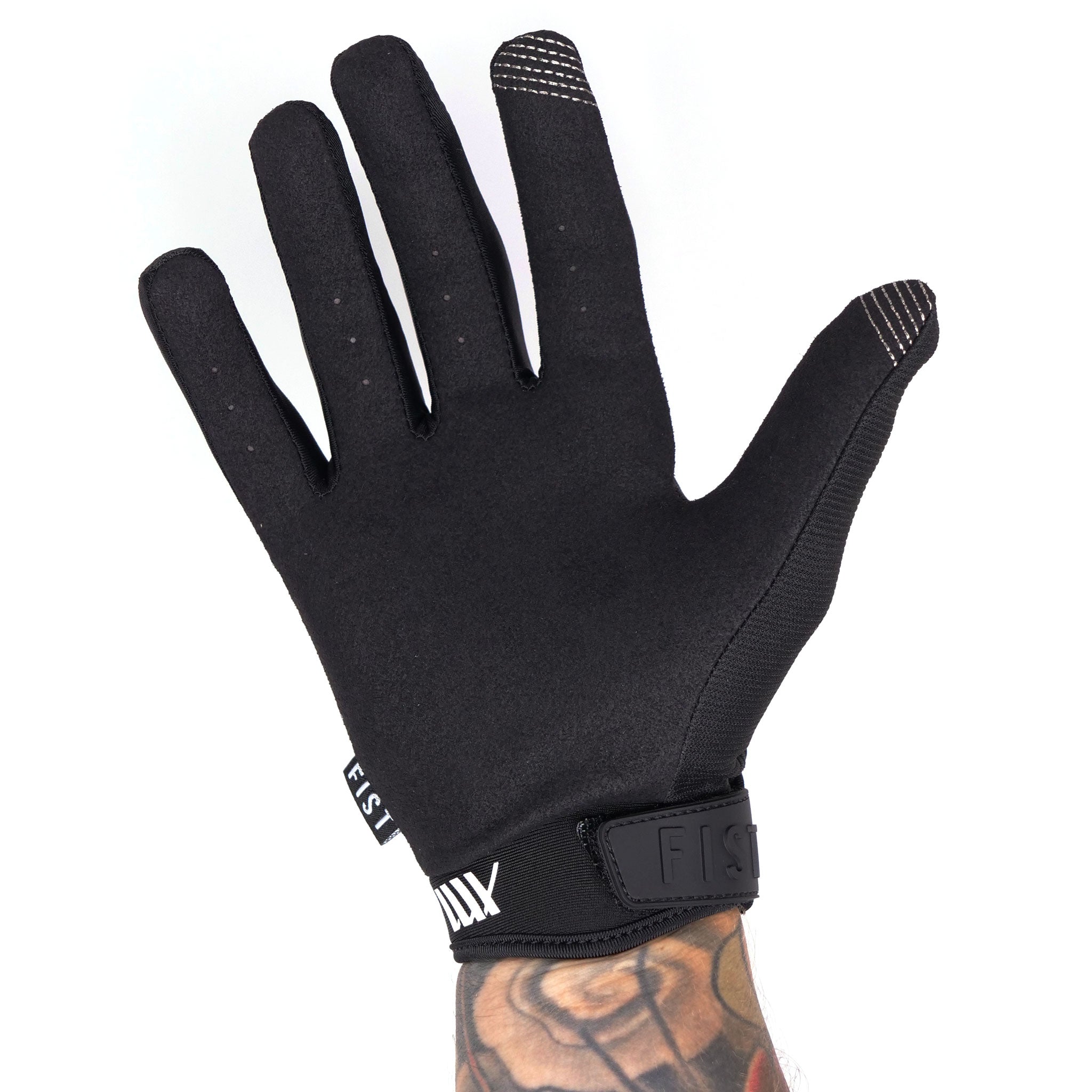 A tattooed hand showcases the durability and style of a black and white LUXBMX X FIST V2 Glove, featuring reinforced stitching.