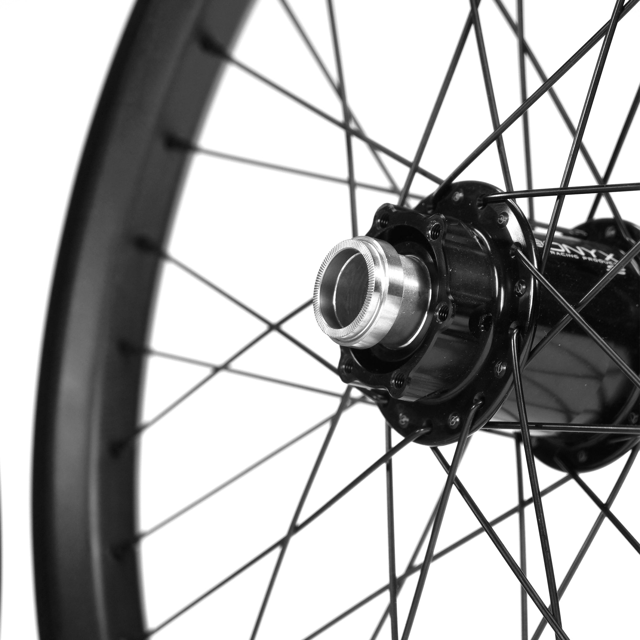 Close-up of a BMX wheel from the Onyx X Spectre Carbon Battlesnake Black 20 Inch Wheelset, featuring a shiny metal hub and radial-patterned spokes. The carbon fiber outer rim is in focus, highlighting its sleek design.