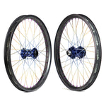 Two Onyx X Spectre Carbon Marble Sunset 20-inch wheels with sleek black rims and blue hubs showcase striking titanium spokes in gold and silver, displayed against a pristine white background.