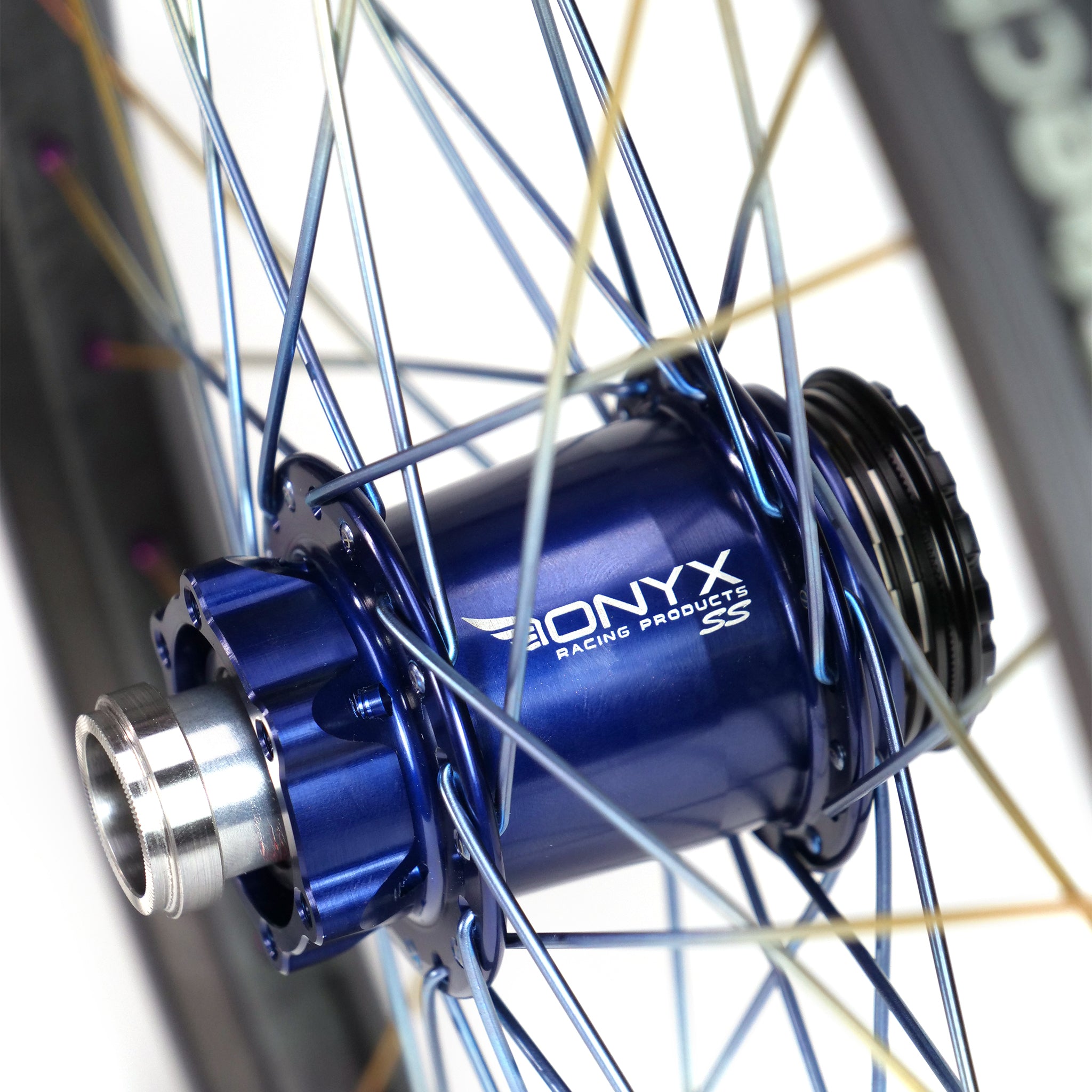 Close-up of a blue Onyx hub with titanium spokes and silver detailing, perfectly complementing the branding on the Onyx X Spectre Carbon Marble Sunset 20 Inch Wheelset.