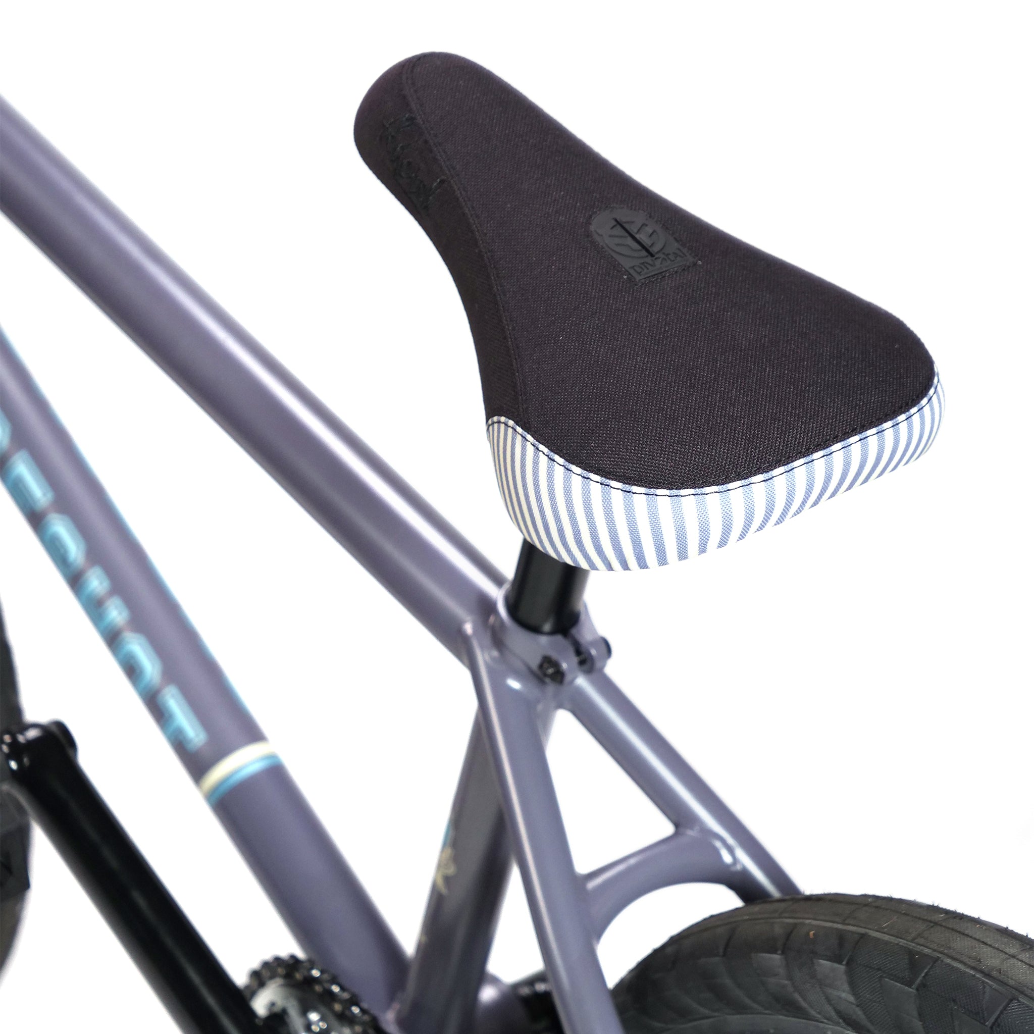 Close-up of a black bicycle seat with striped edges, mounted on the gray frame of a BSD Long Shot Custom BMX Bike. The rear wheel and part of the frame are visible.