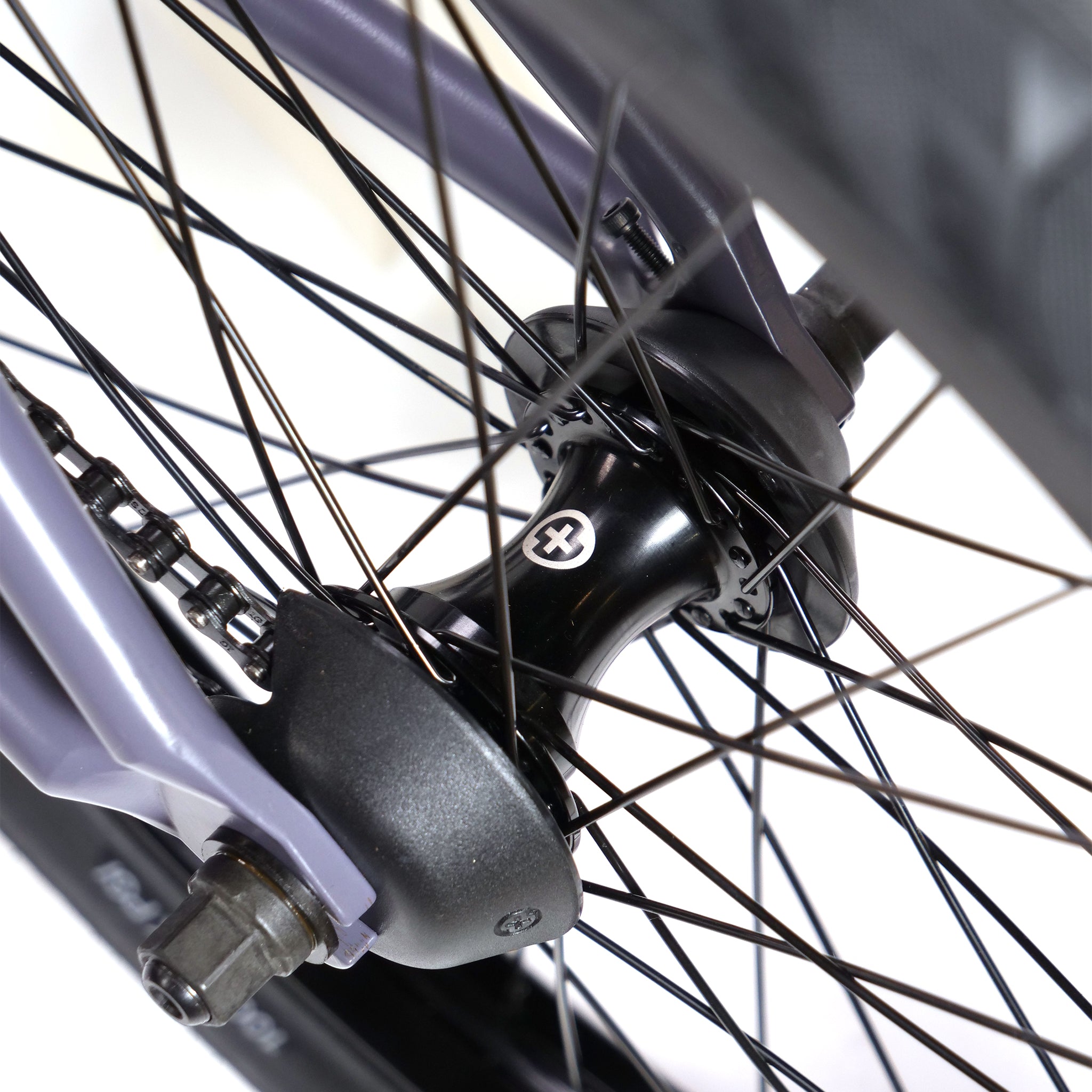 Close-up of the BSD Long Shot Custom BMX Bike's rear wheel, highlighting the hub, spokes, and frame part. The black hub features a white cross symbol.