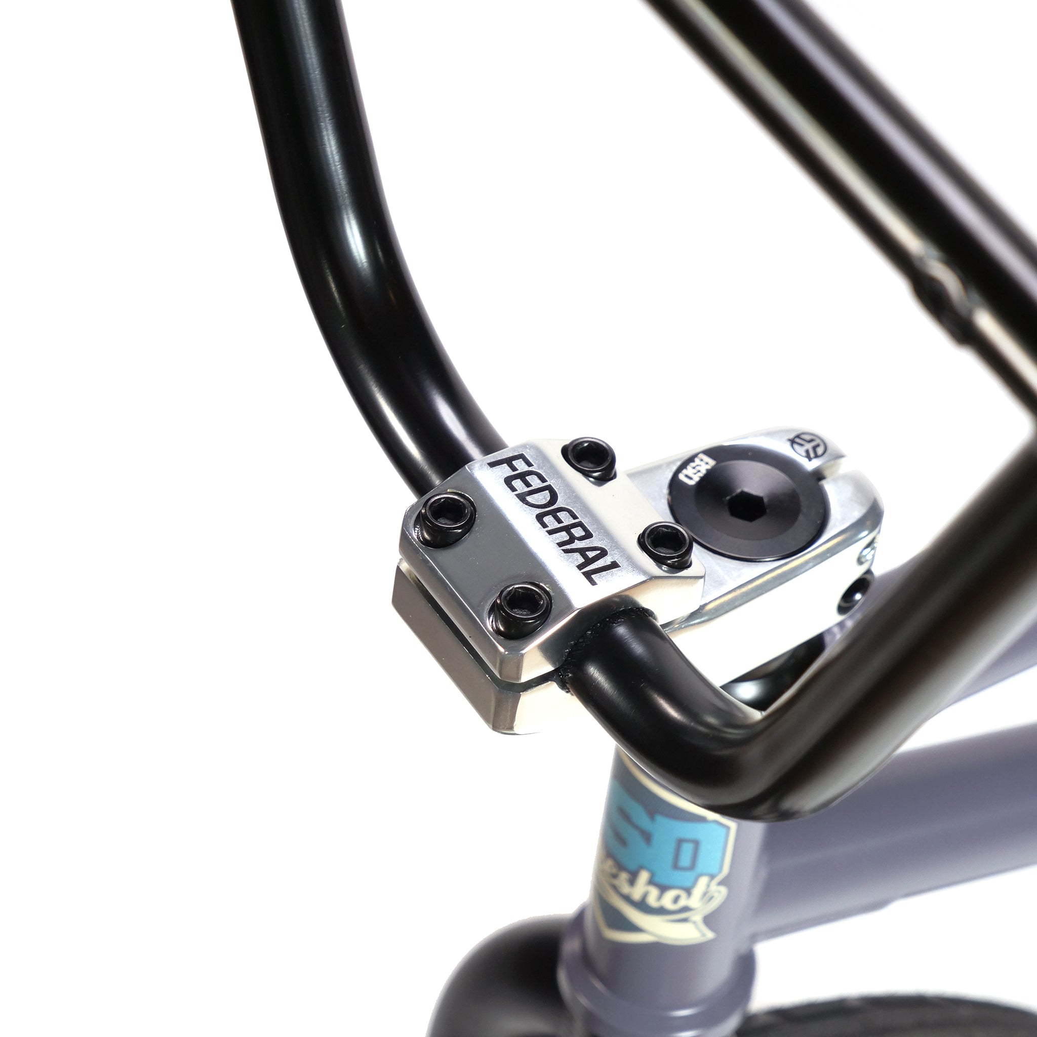 Close-up of BSD Long Shot Custom BMX Bike handlebars and stem, labeled "FEDERAL." The silver stem features black bolts connecting to black handlebars with the bike frame visible below.