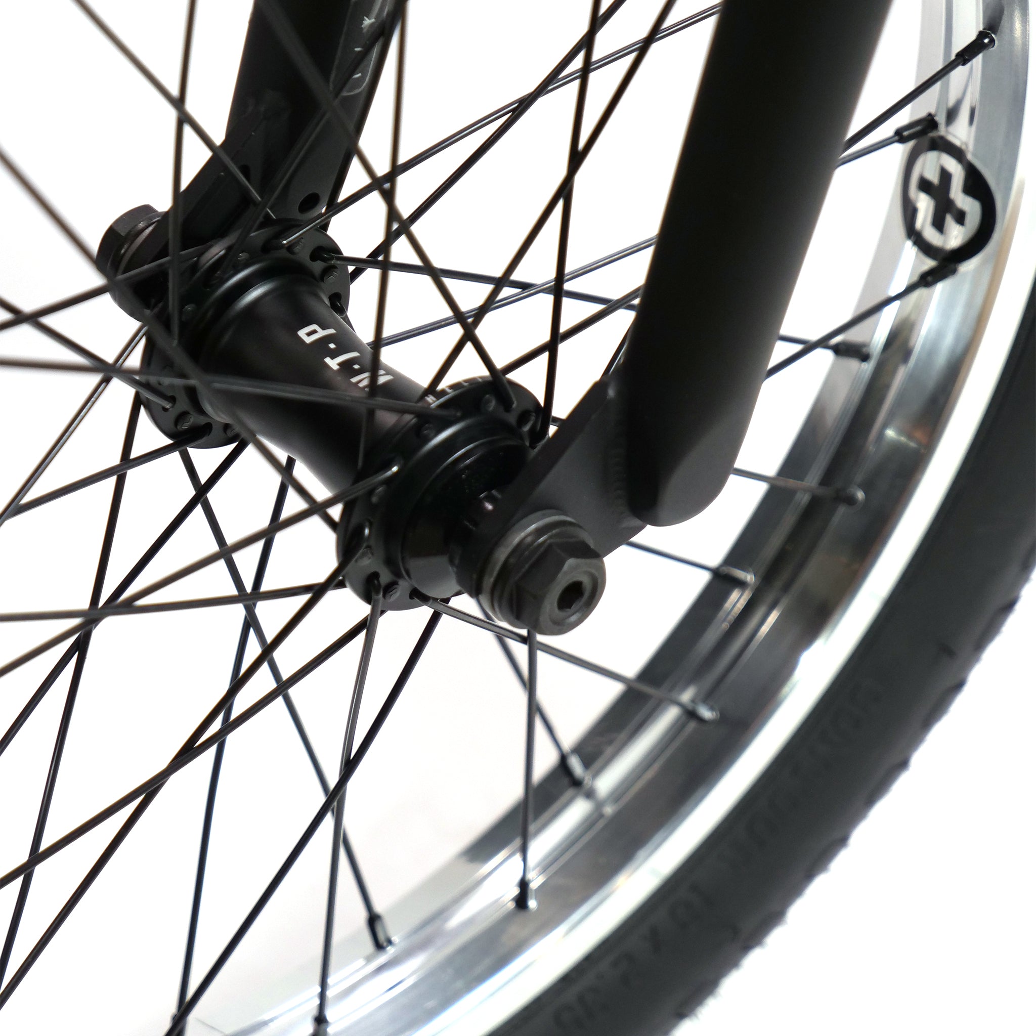 A close-up view of the Fly Bikes Pajarito Custom 18 Inch BMX Bike shows its black front wheel, featuring a black hub and spokes, as well as a partially visible black tire.