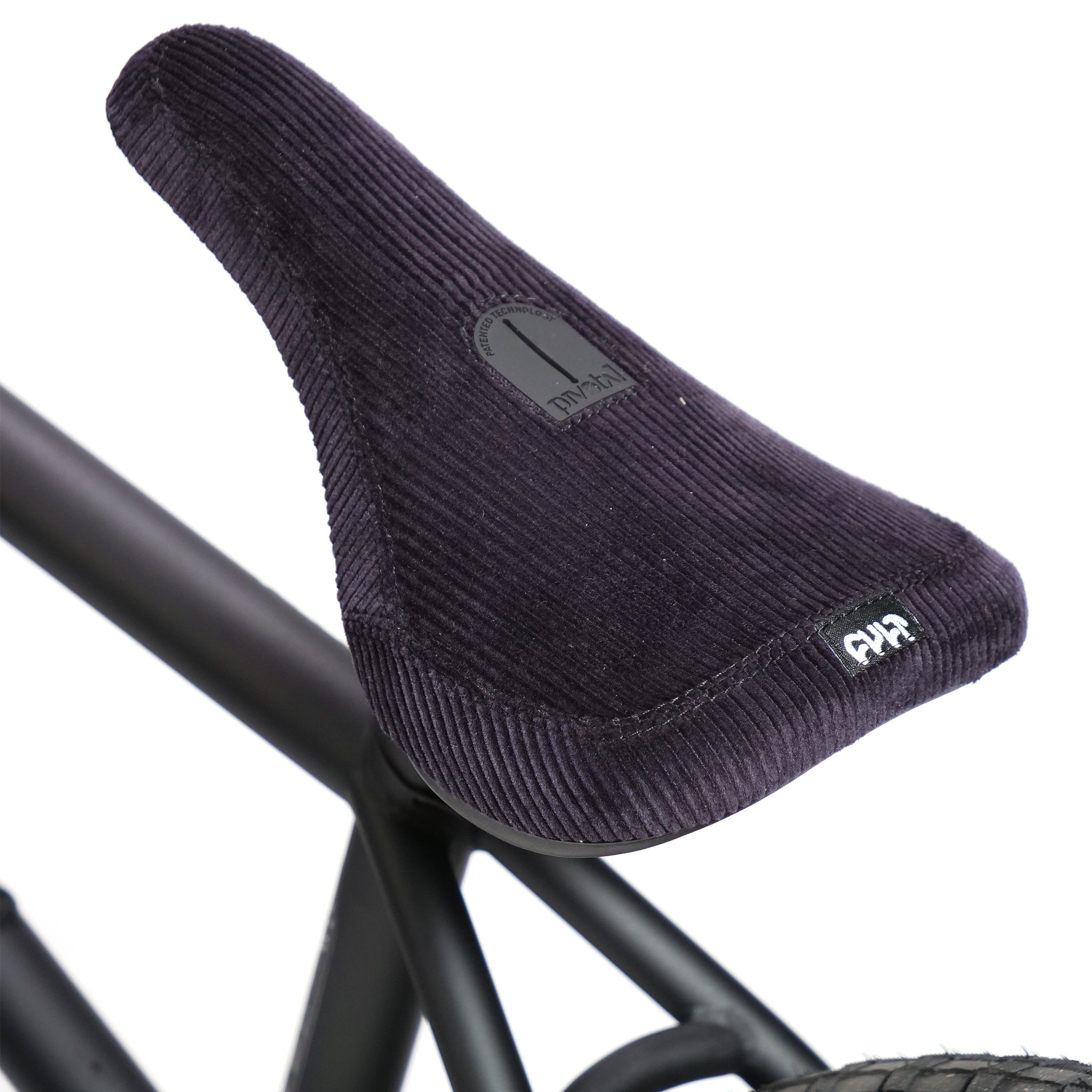 Close-up of a black corduroy bicycle seat with a logo on the back, attached to the Fly Bikes Pajarito Custom 18 Inch BMX frame.